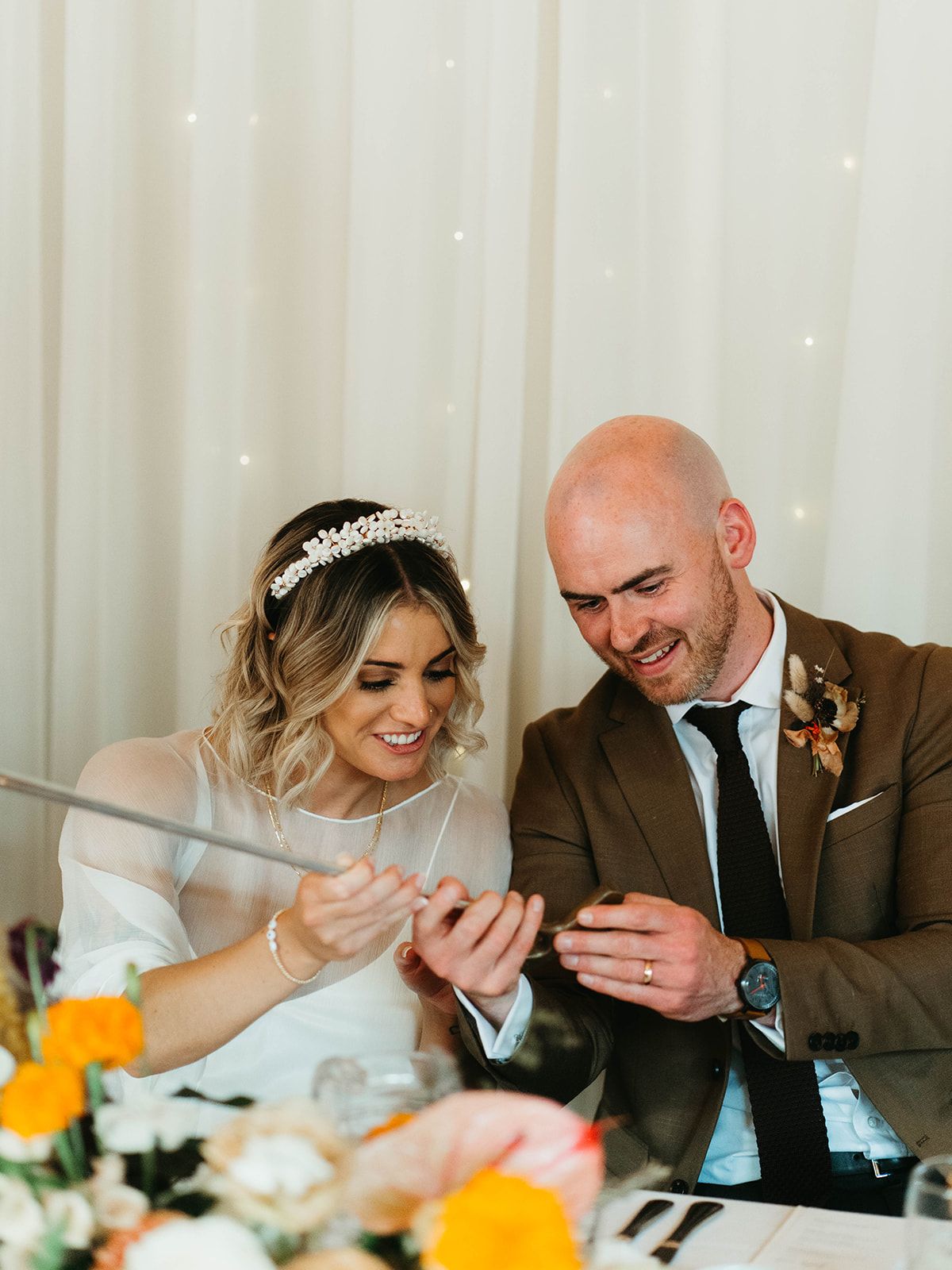 Happy couple sharing a joyful moment at their reception table decorated with orange citrus centerpieces.