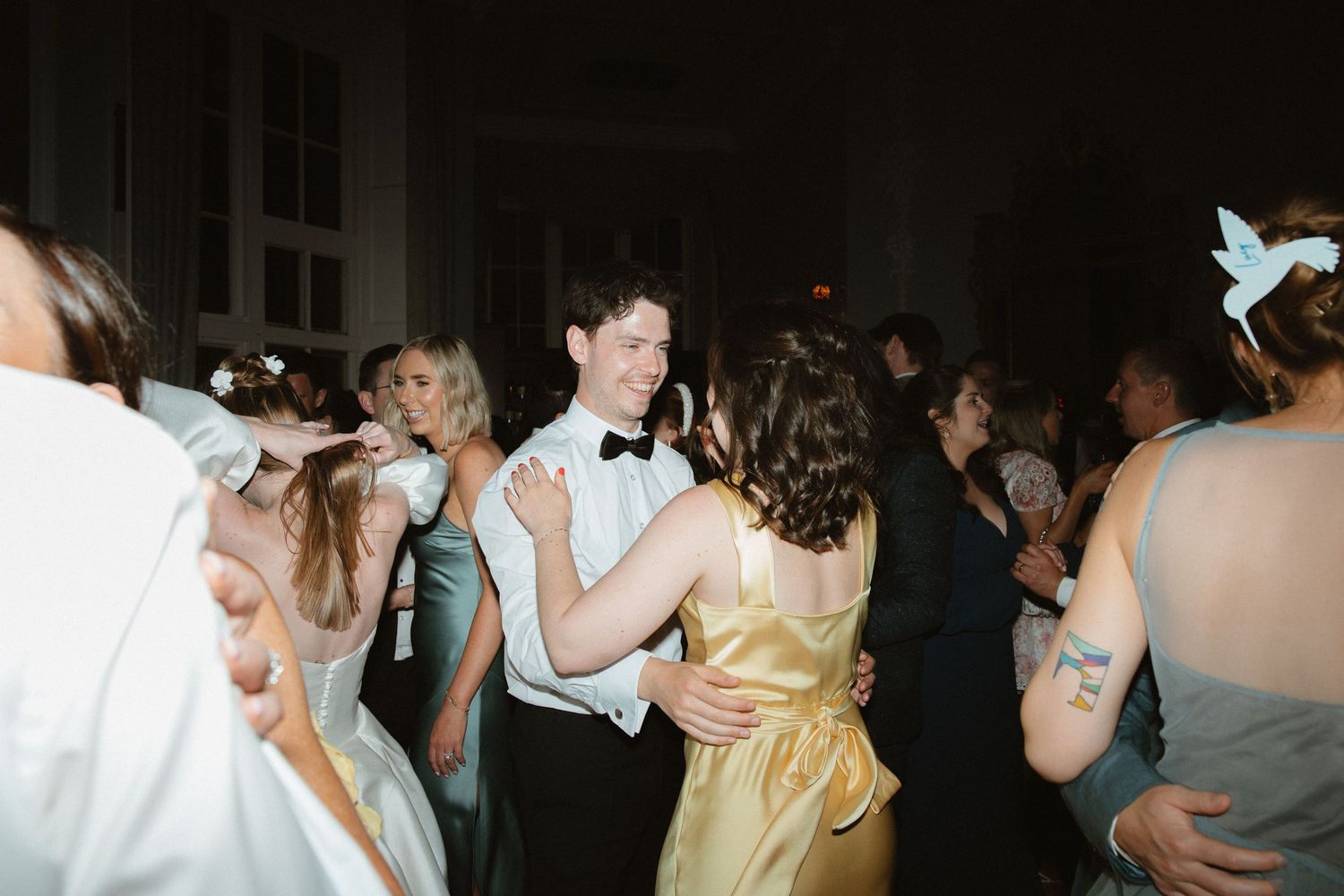 A group of people dancing together in a dimly lit room at what appears to be a party or celebration event.