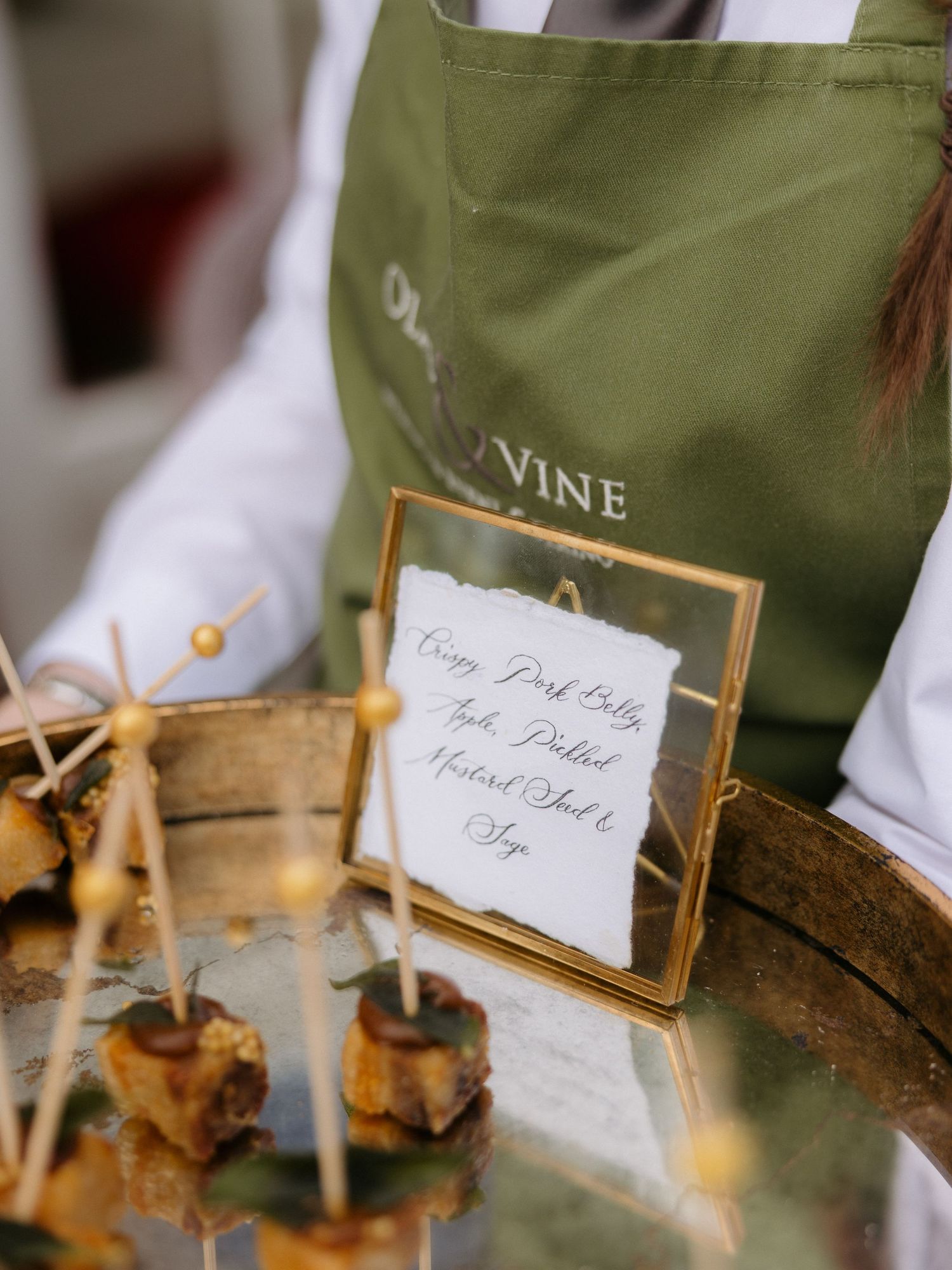 Small appetizers served on wooden boards with elegant name cards and toothpicks at an upscale catering event.