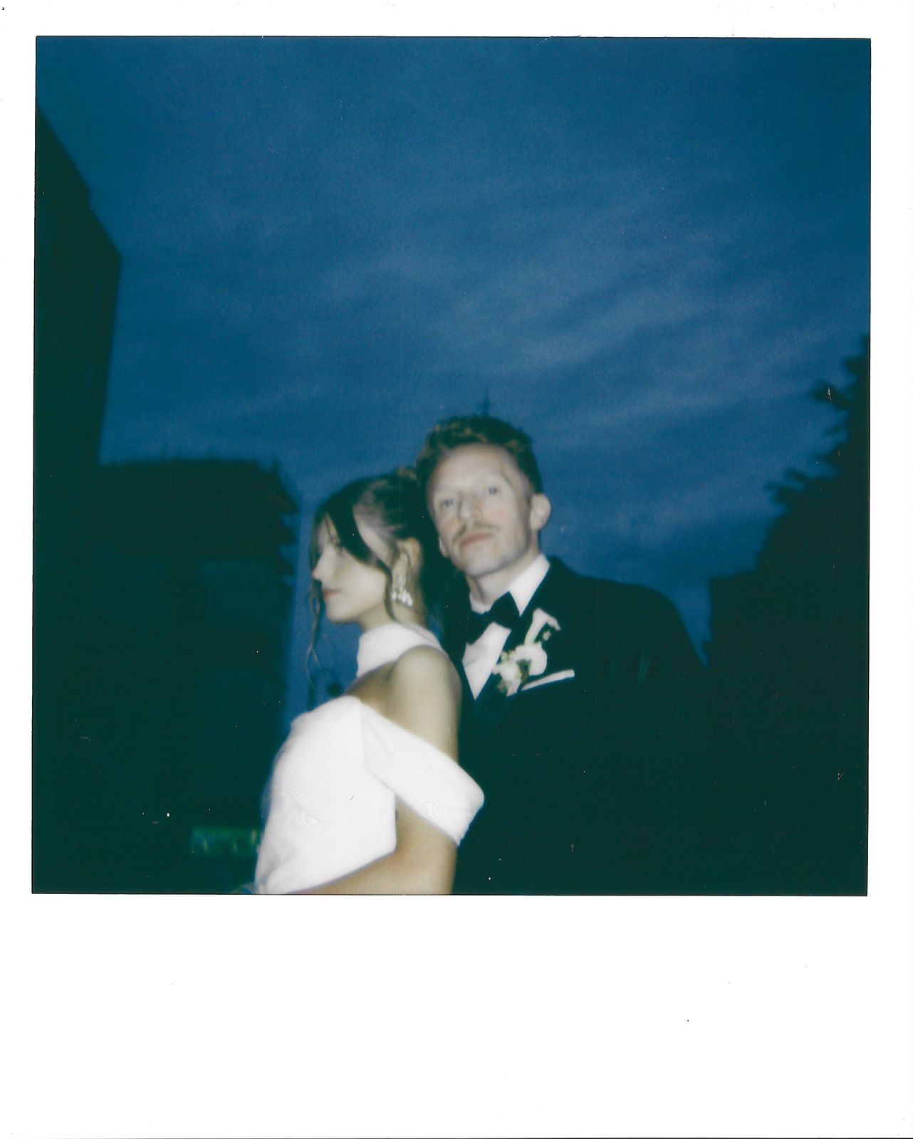 Two people embrace and dance under a dramatic dark blue evening sky.