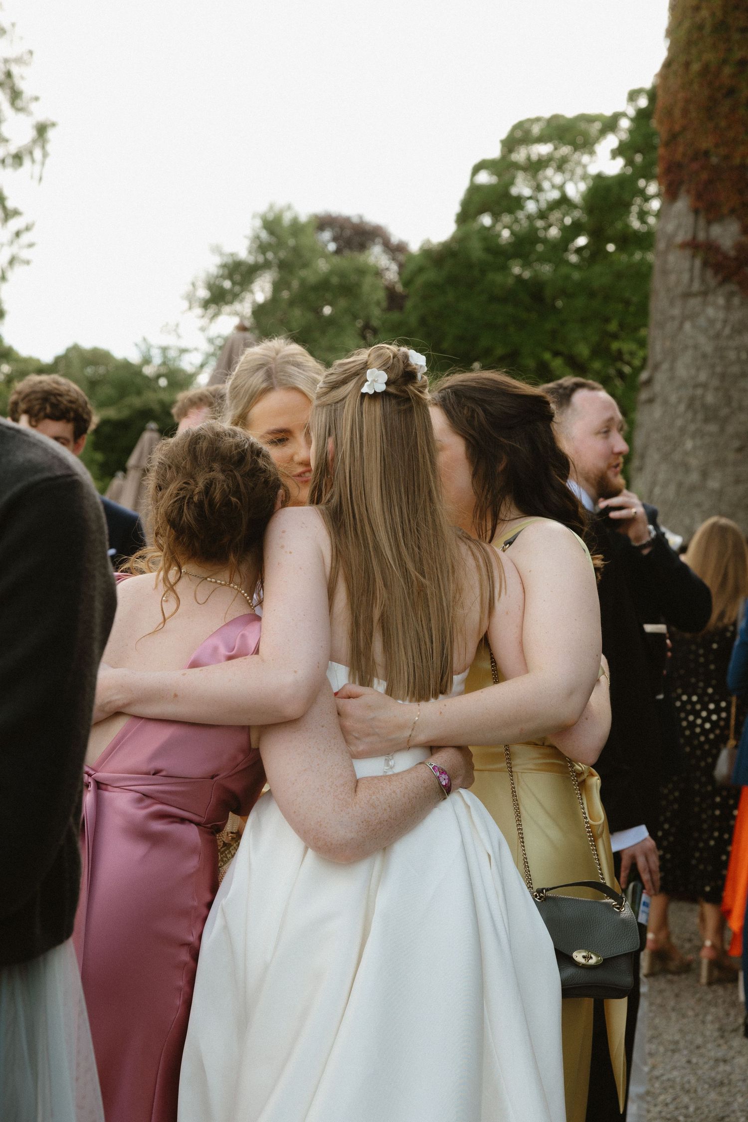 Intimate group hug shared during an outdoor wedding celebration.