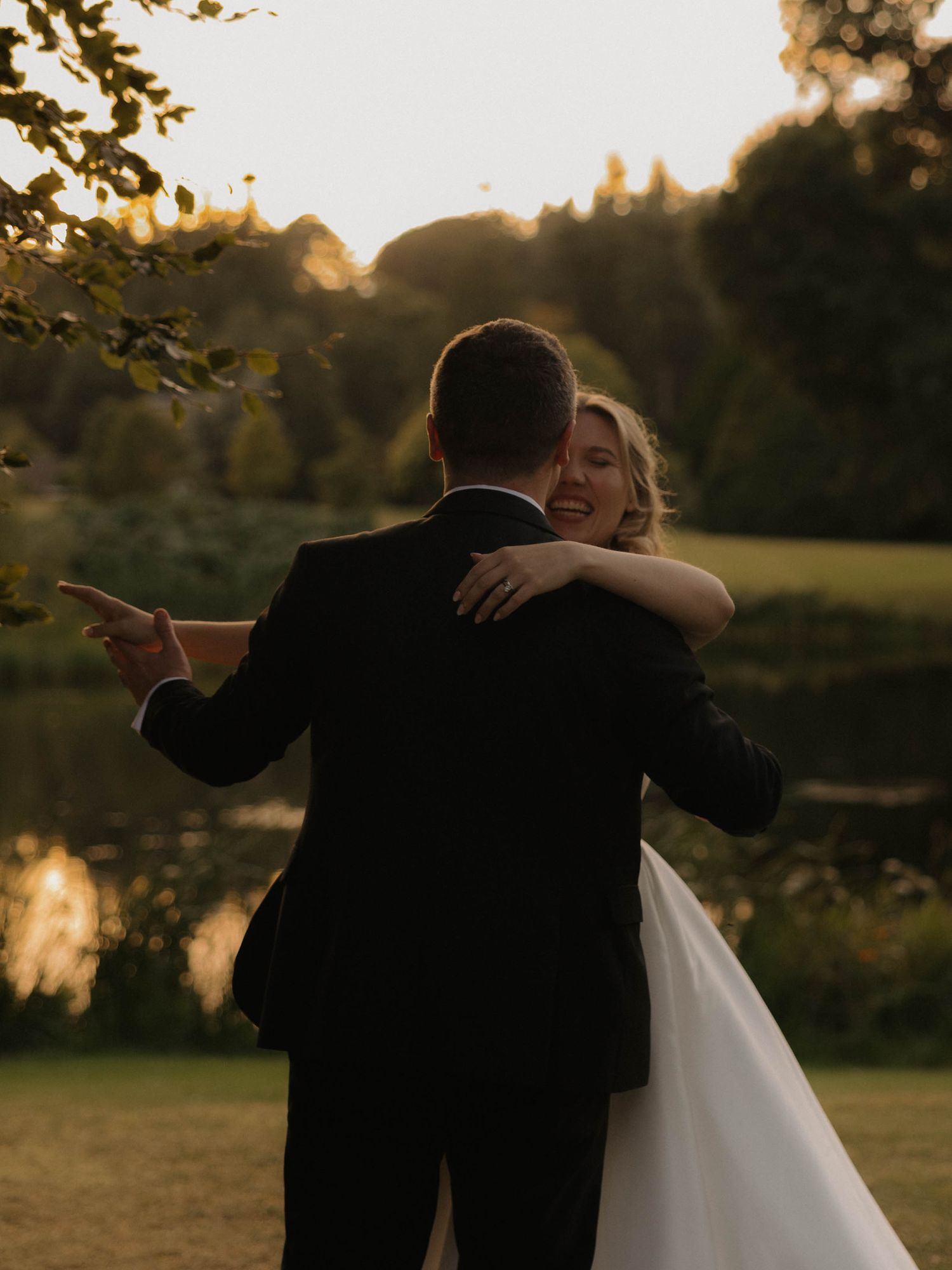A couple embraces in a romantic golden sunset moment in an outdoor garden setting.