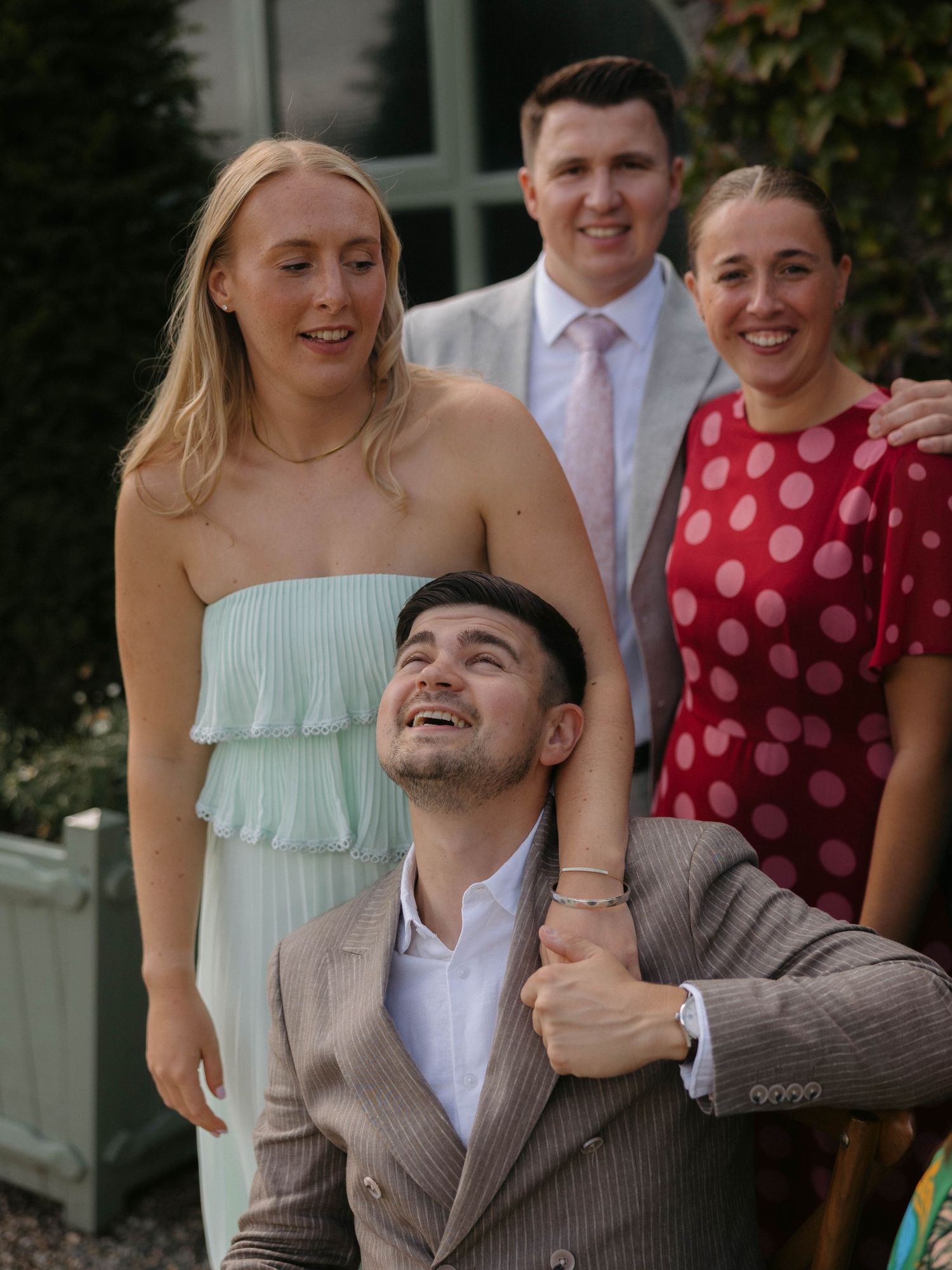 Wedding guests pose together outdoors wearing summer formal attire.