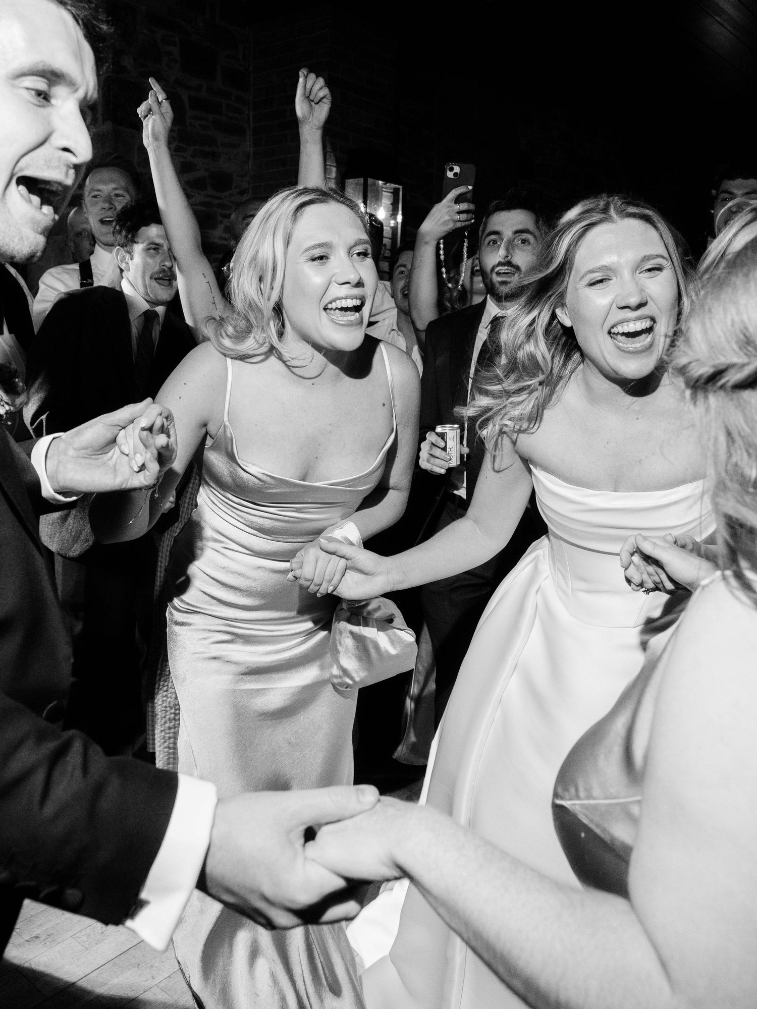 Wedding reception guests dancing and celebrating in black and white photography.