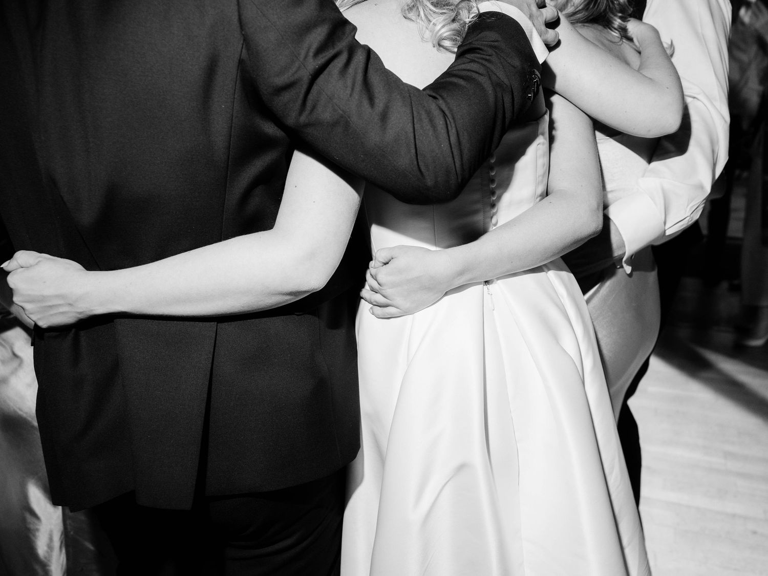 Black and white photo of couples dancing together at a formal event, with focus on elegant dress and suit attire.