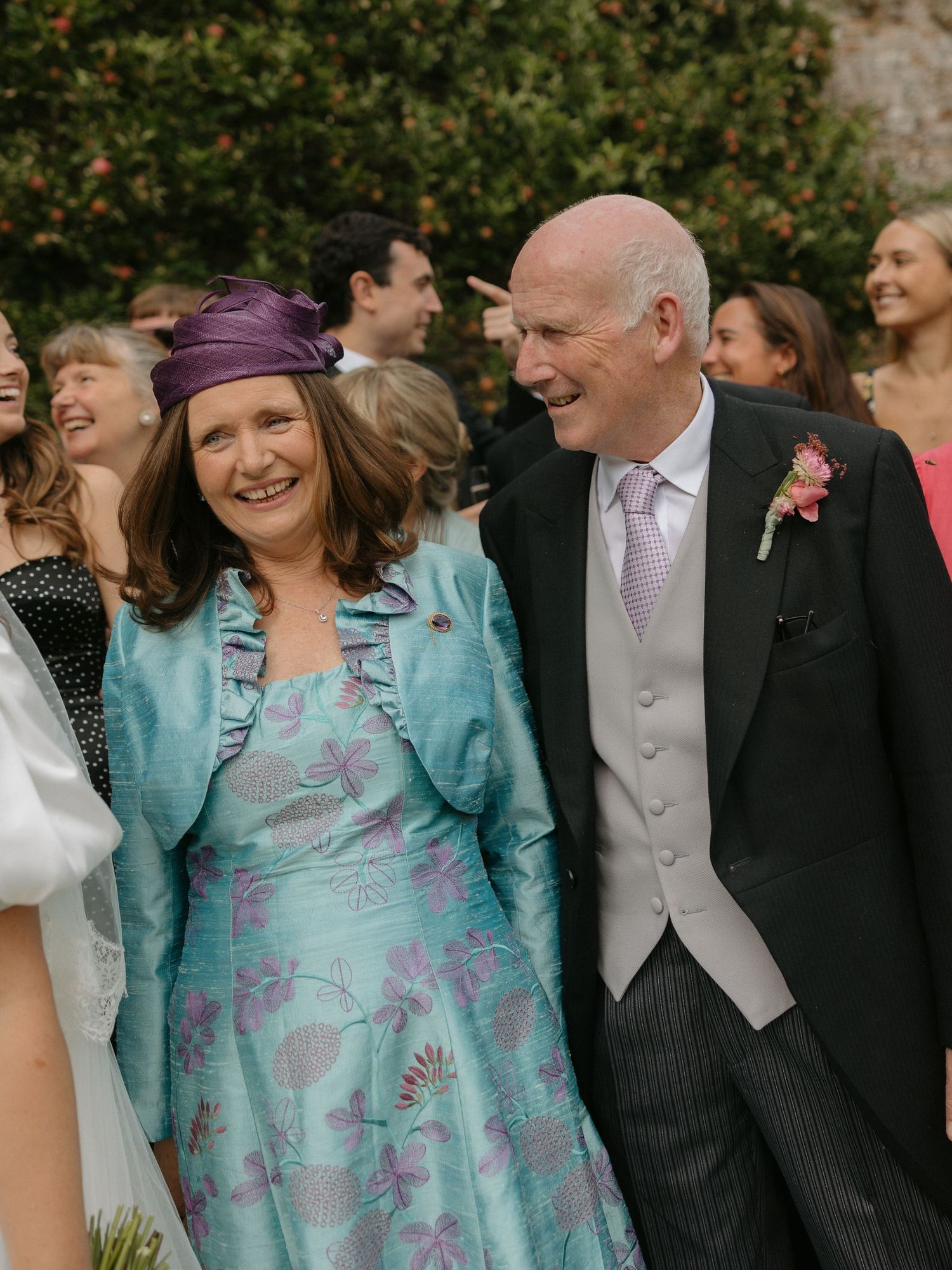 Wedding guests share laughter and joy during an outdoor celebration in formal attire.