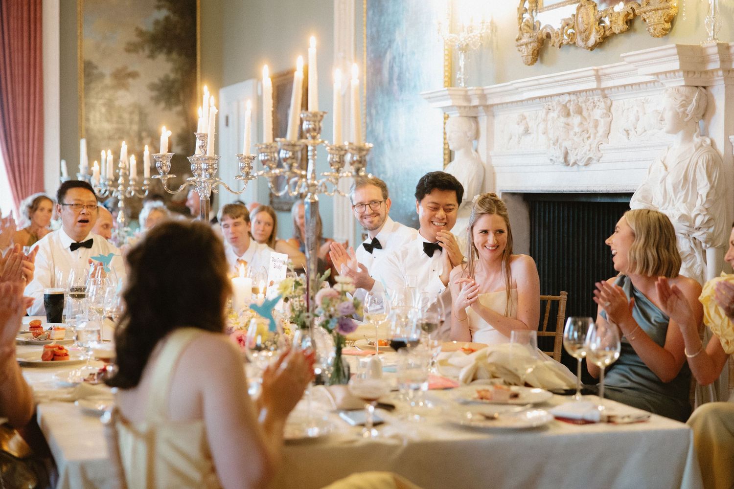 Wedding guests enjoying a meal at a formal dinner table with candles and elegant decor.
