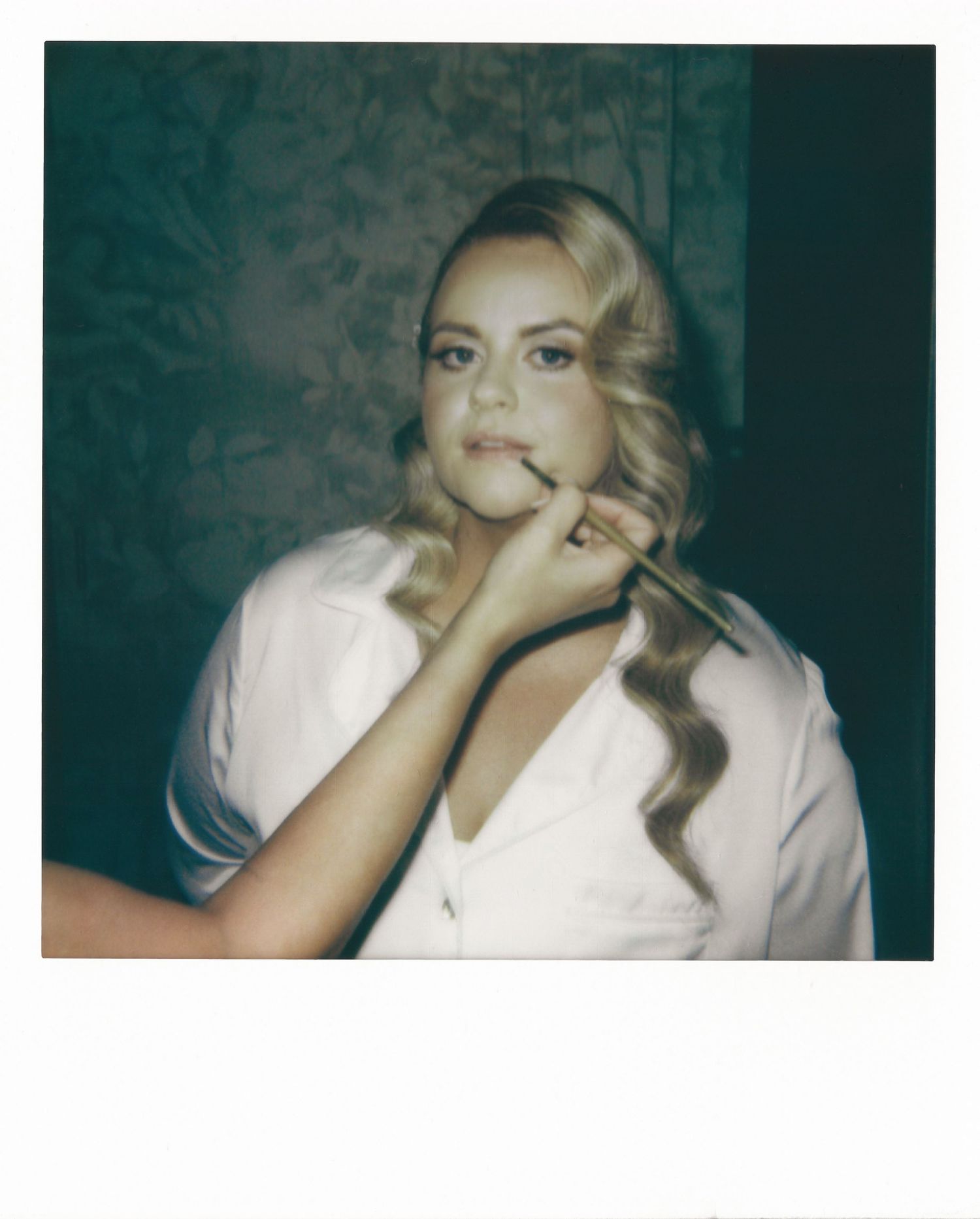 A person in a white top poses against a dark background in a vintage-style photoshoot series.