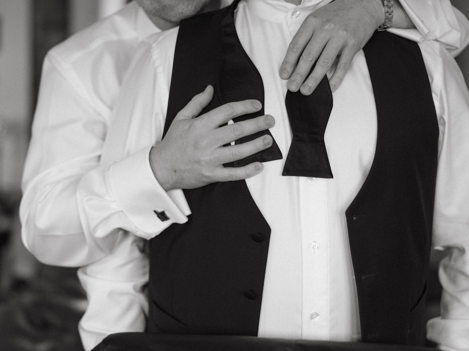 Close-up details of formal wedding attire showing white dress and black tuxedo.