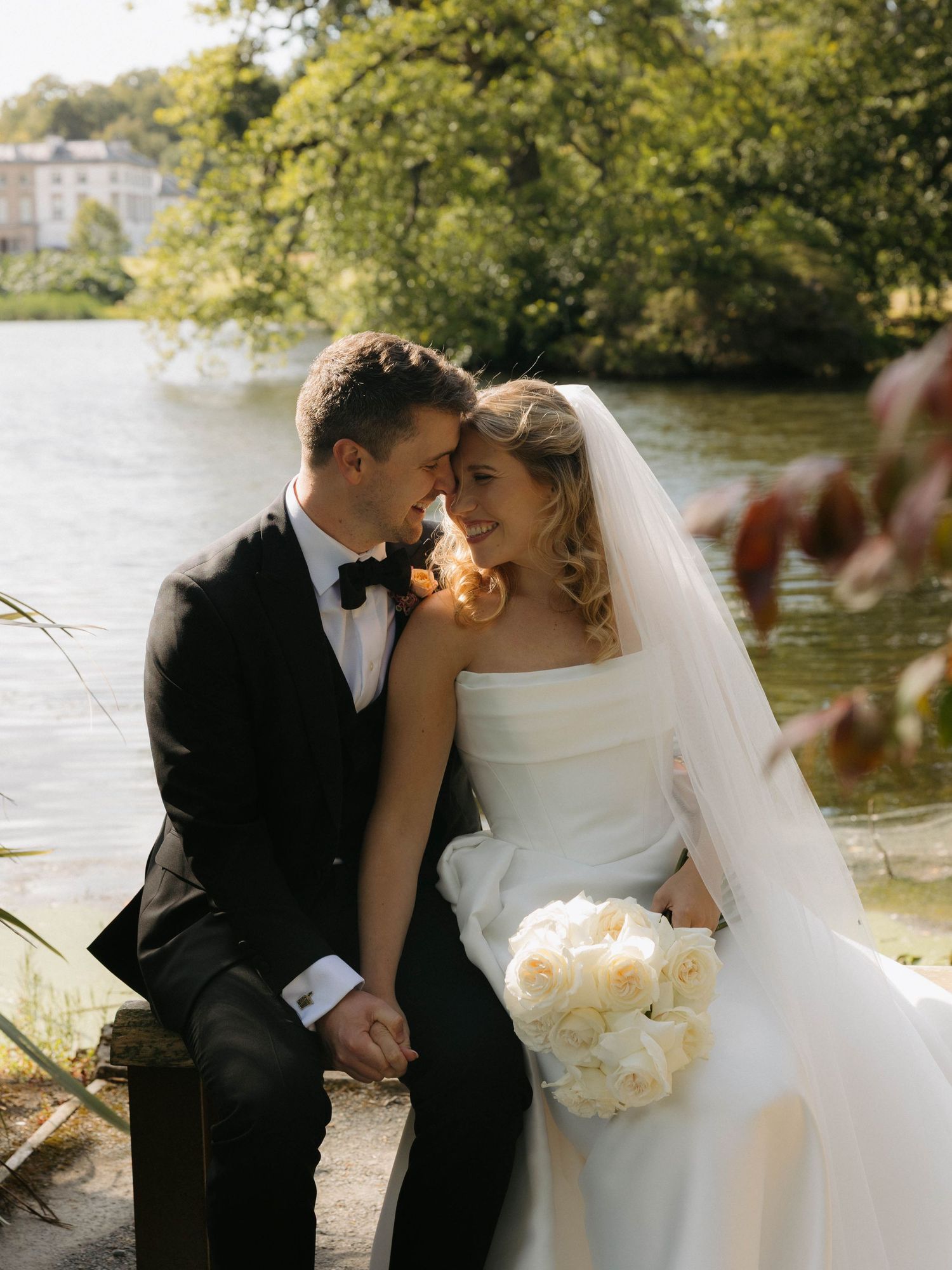 Romantic wedding portraits by a serene lakeside with natural lighting.