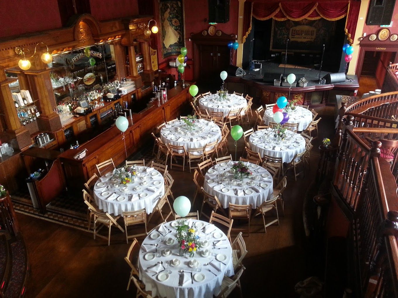 Elegant wedding reception venue with round tables set with white linens and floral centerpieces in a rustic banquet hall.