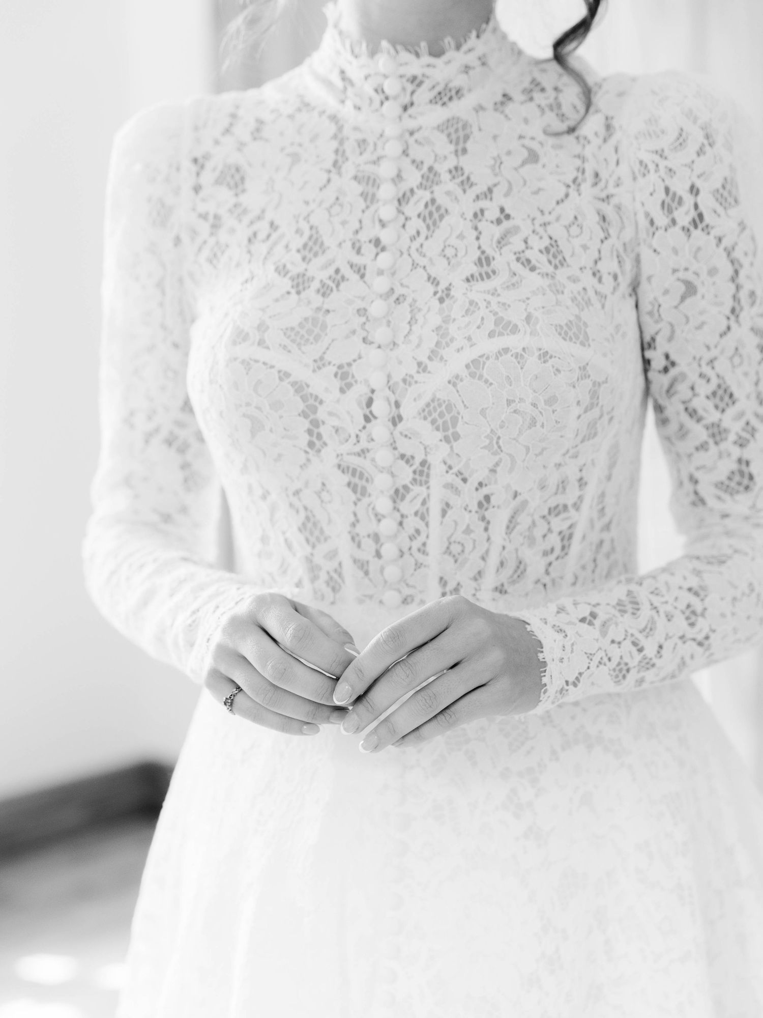 Elegant white lace wedding dress with high neck and long sleeves shown in black and white photography.