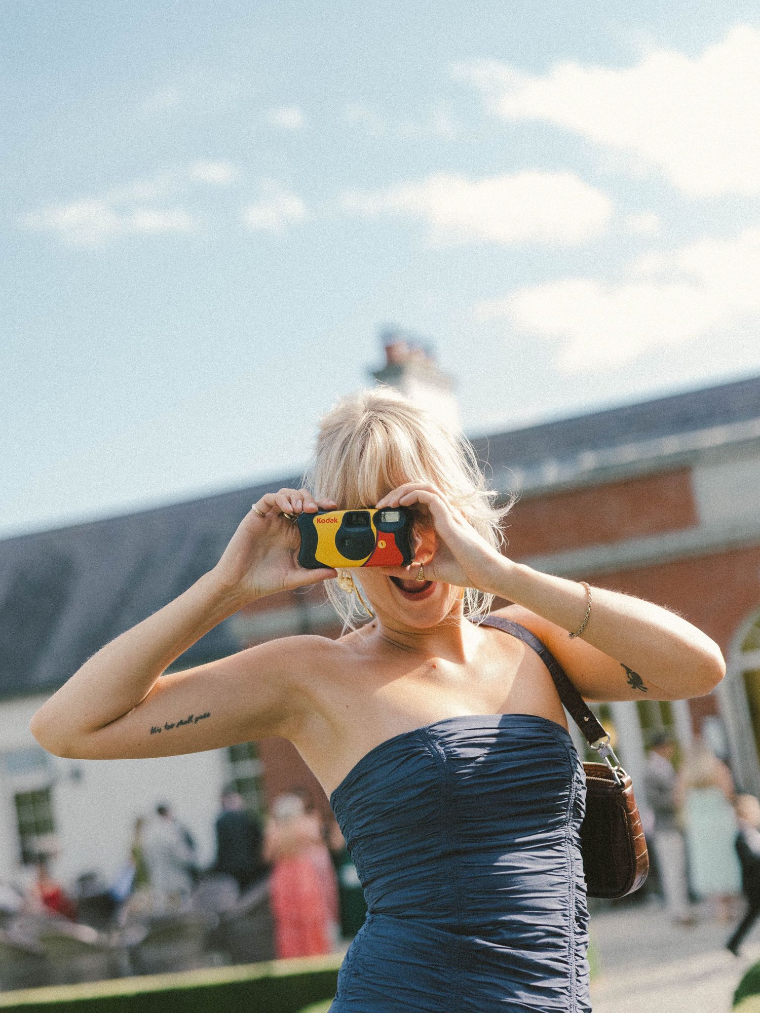 A sequence of photos shows a person in a blue strapless dress taking pictures with a vintage camera outdoors.