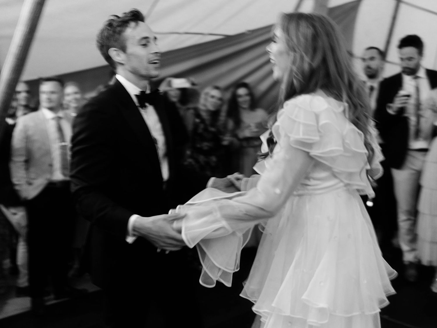 Black and white photo of couple dancing energetically at their wedding reception.