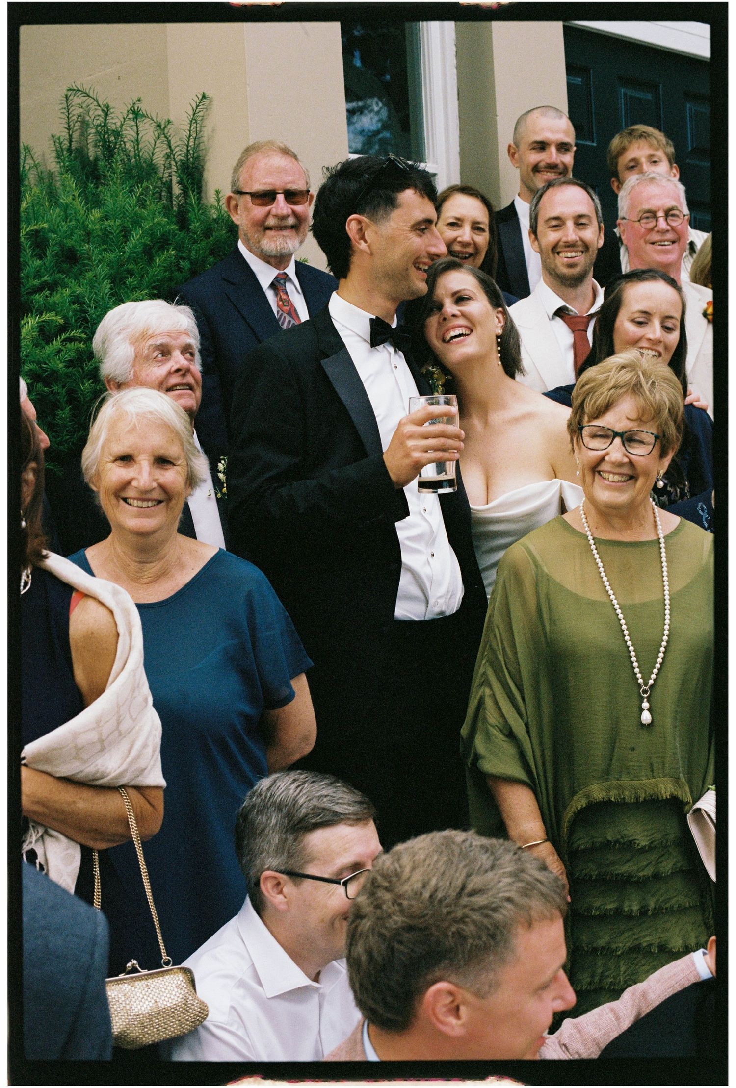 Happy bride and groom posing with wedding guests on outdoor steps.