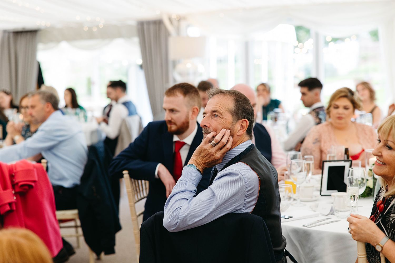 Wedding guests share emotional reactions while watching a touching moment during a reception at an elegant venue.