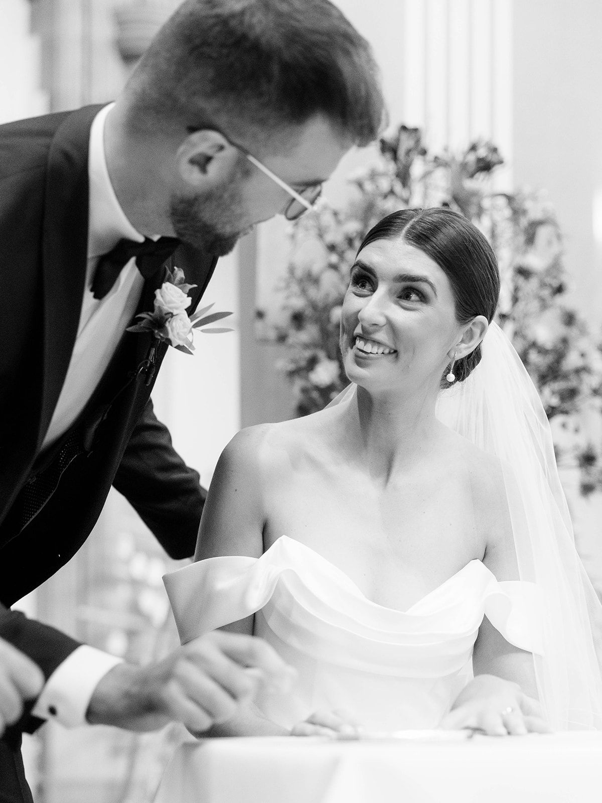Black and white wedding moment captured as couple shares intimate conversation during their reception celebration.
