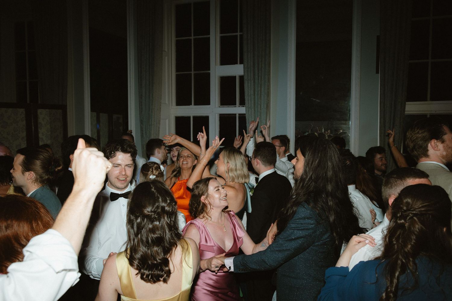 A crowded dance floor filled with people dancing and celebrating at an indoor event venue.