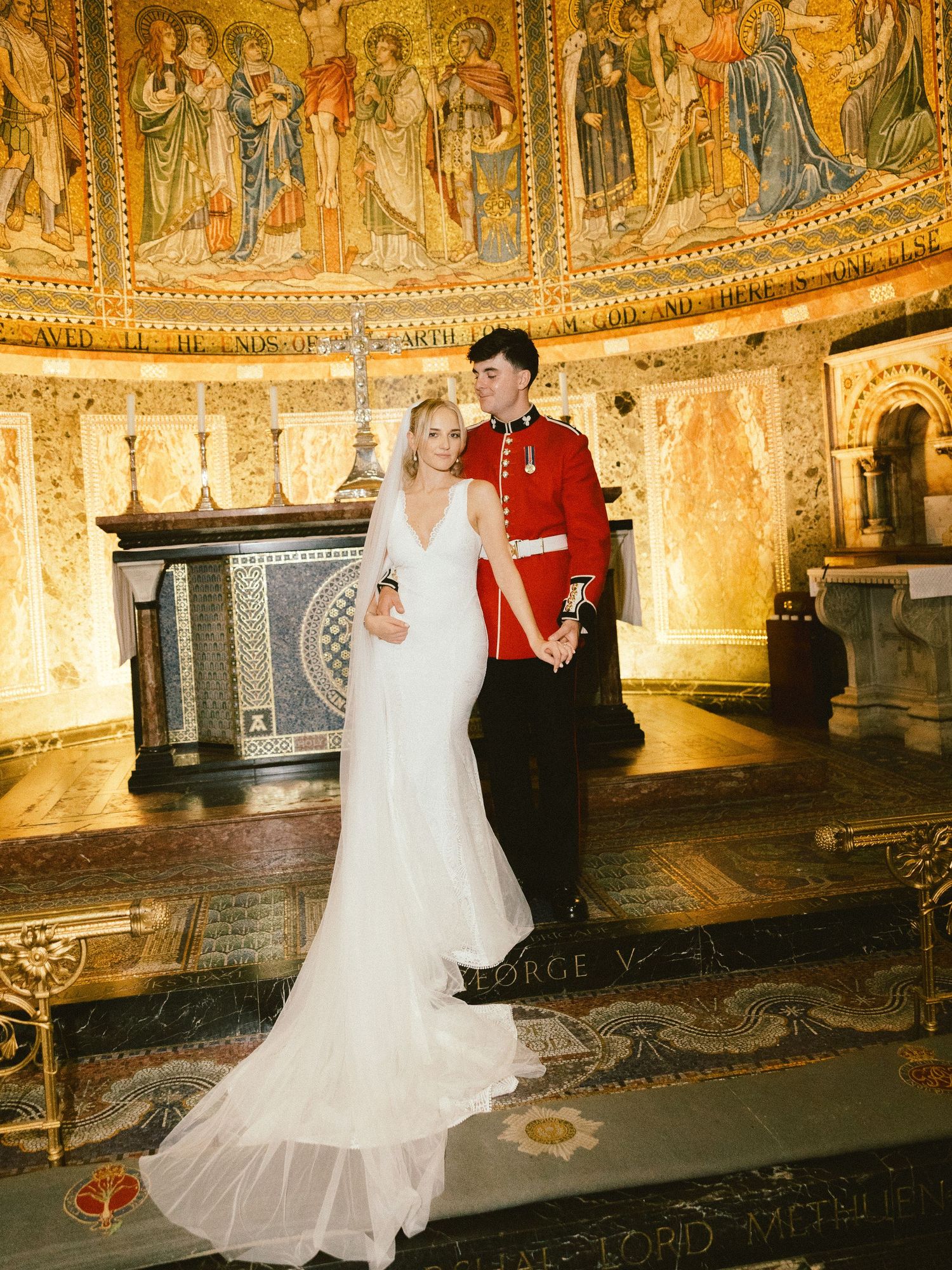 An elegant wedding couple dances in an ornate cathedral hall with beautiful frescoed walls and gilded decor.