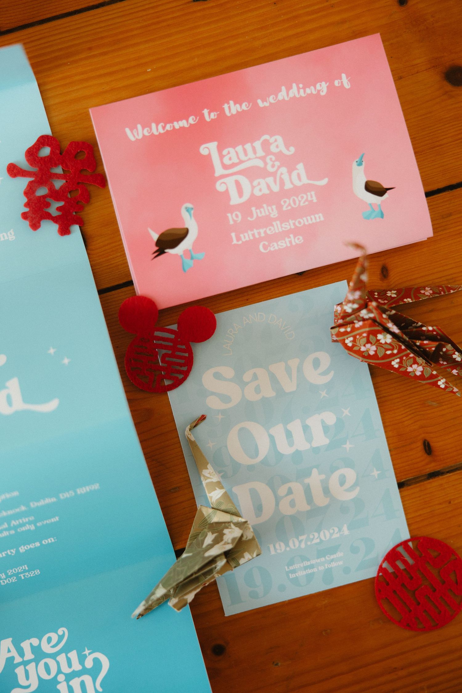 Pink and blue wedding stationery with decorative origami cranes and heart details.