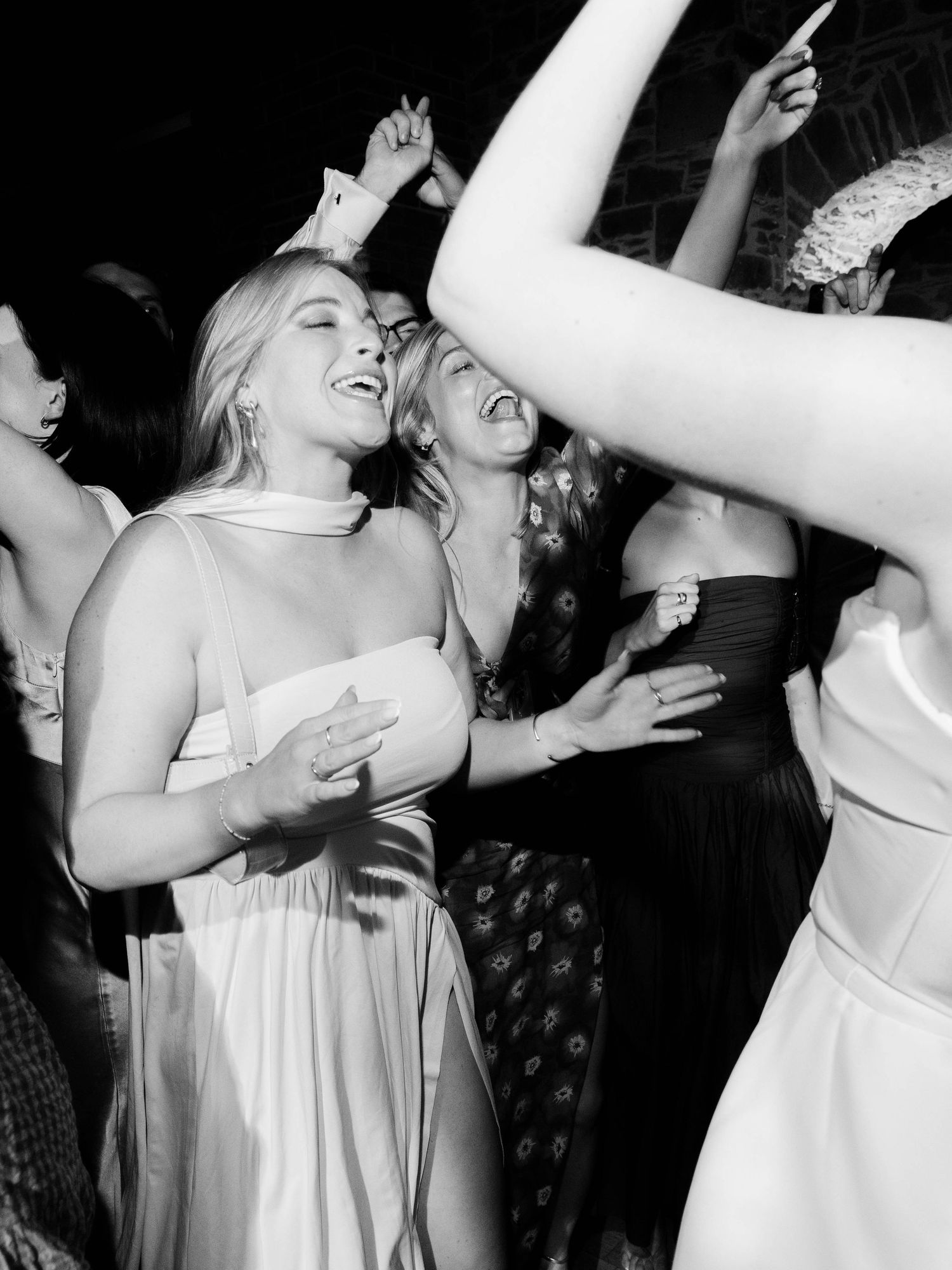 Black and white photo of wedding guests dancing and celebrating on dance floor.