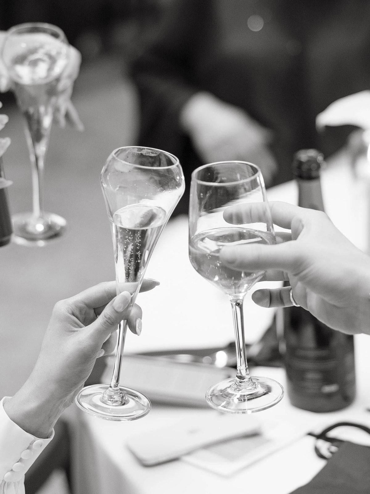 Multiple hands raise wine glasses in a black and white toast sequence showing celebratory dining moments.