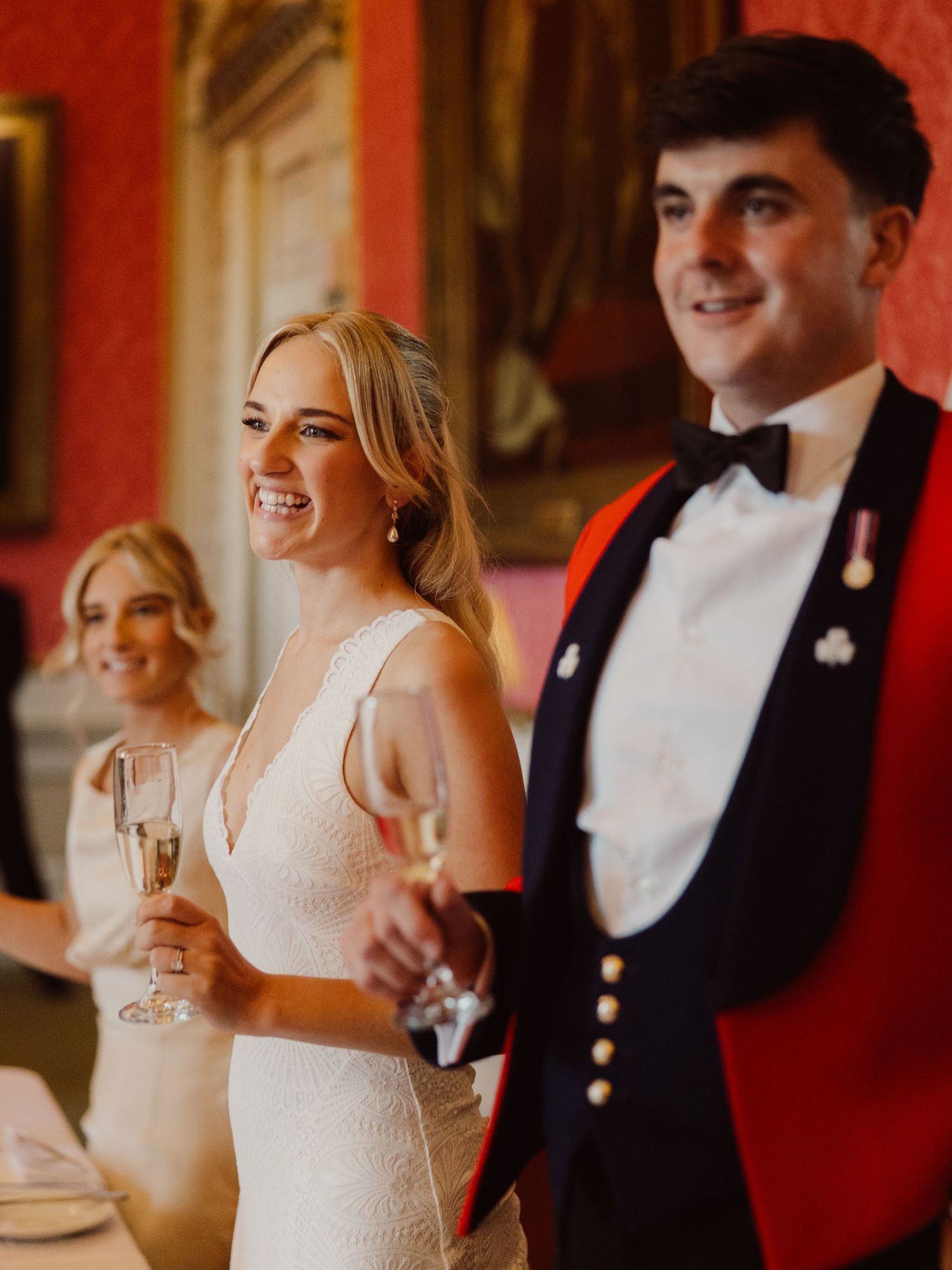 Wedding guests smiling and sharing candid moments during an elegant reception with red-toned lighting and decor.