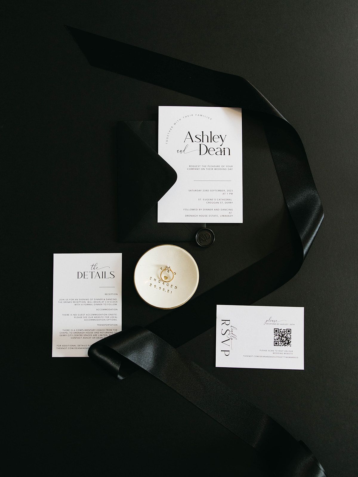 Black and white minimalist wedding invitation suite with cards, details insert, and small ring dish on dark background.