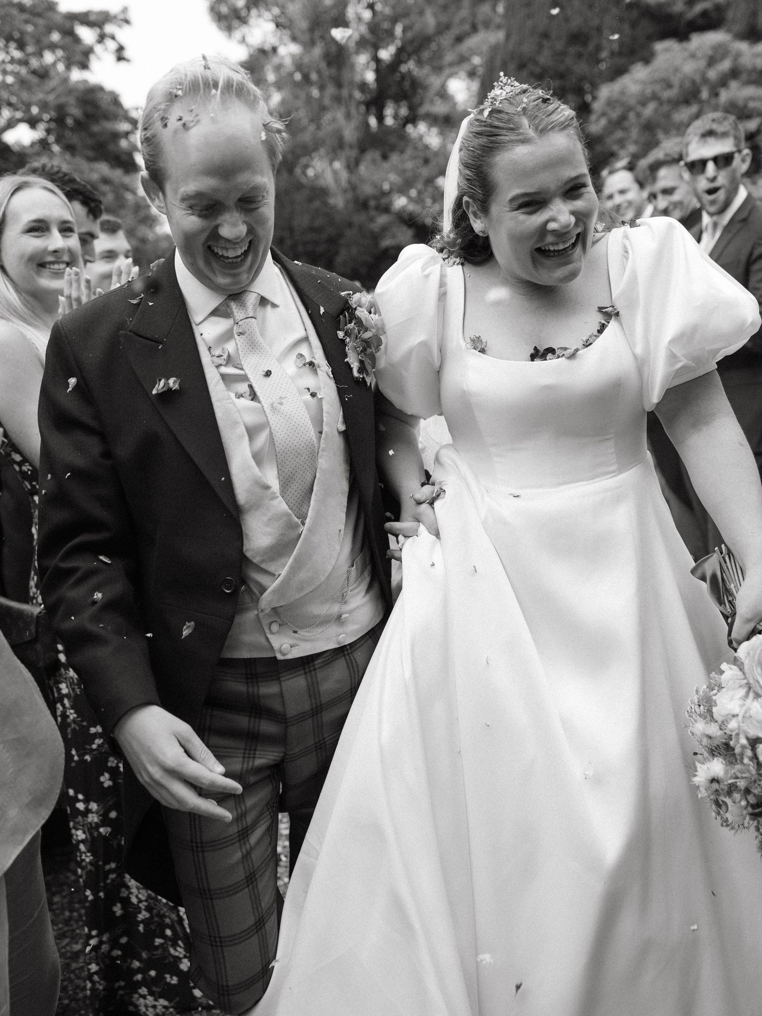 A series of candid black and white wedding photos showing joyful laughter and celebration during outdoor festivities.