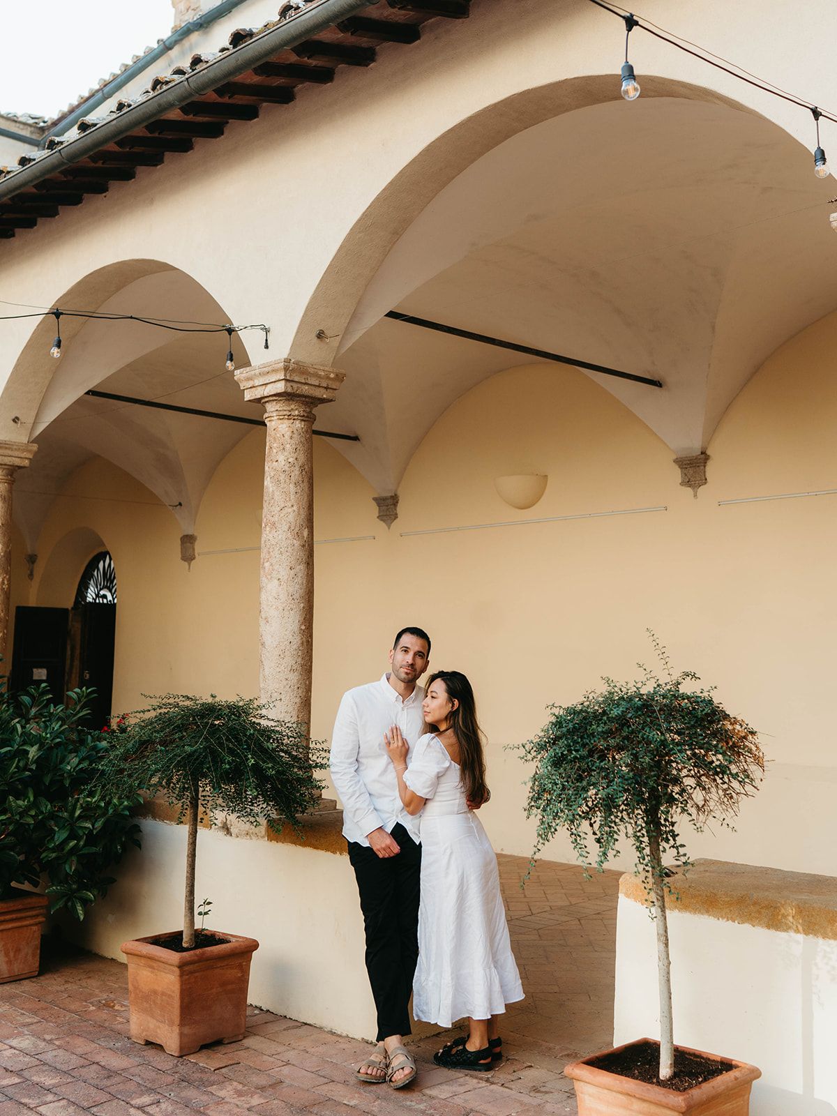 A couple dances under arched columns in a Mediterranean courtyard.