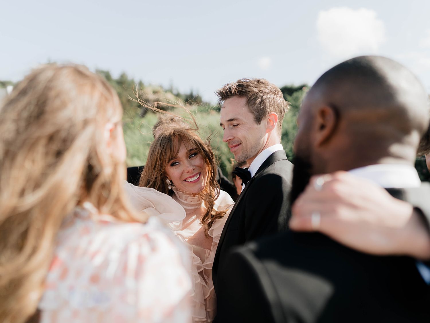Candid moment of wedding celebration with guests laughing on a coastal background.