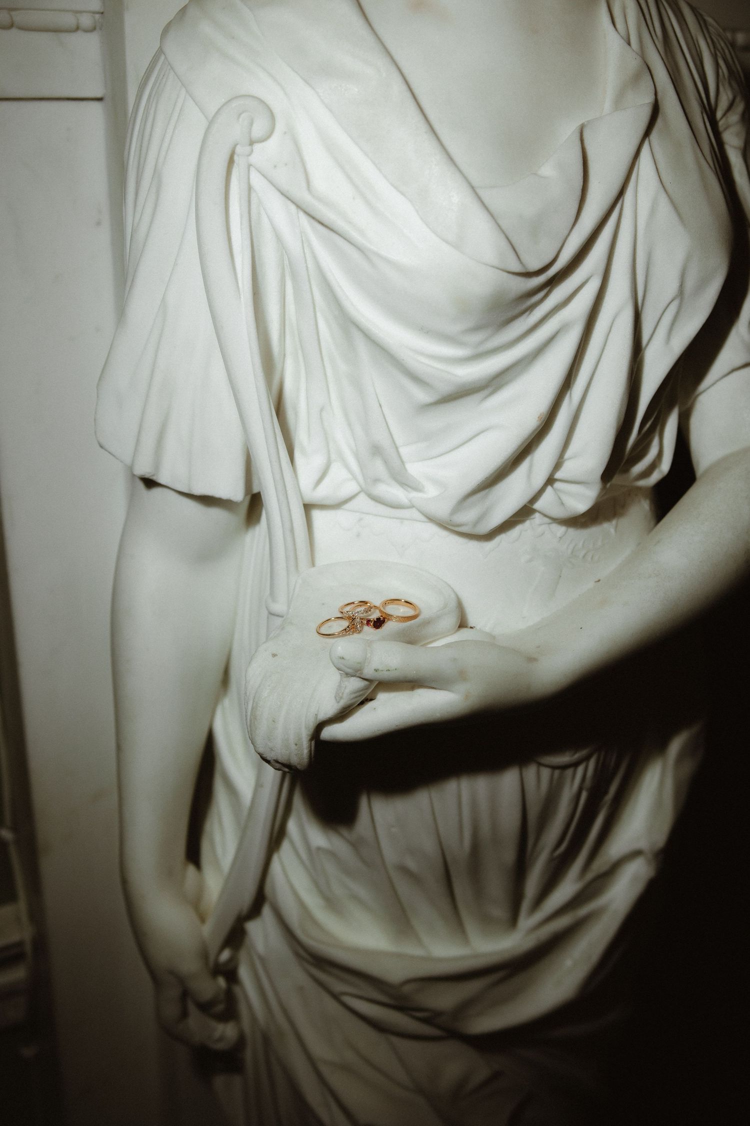 Classical white marble statue detail showing draped fabric and hand.