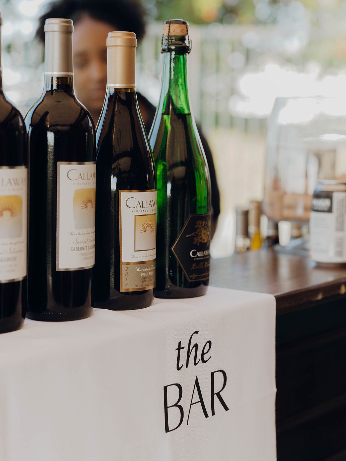 A selection of wine bottles displayed on a bar counter with 'the BAR' text written on the white surface.