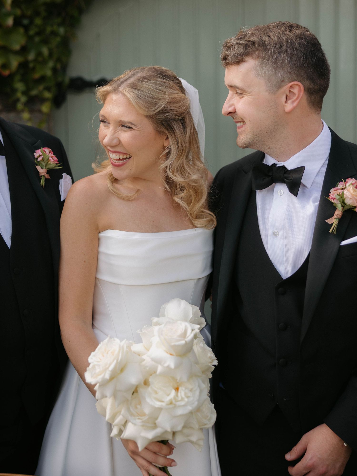 Candid wedding couple moment against green foliage backdrop.