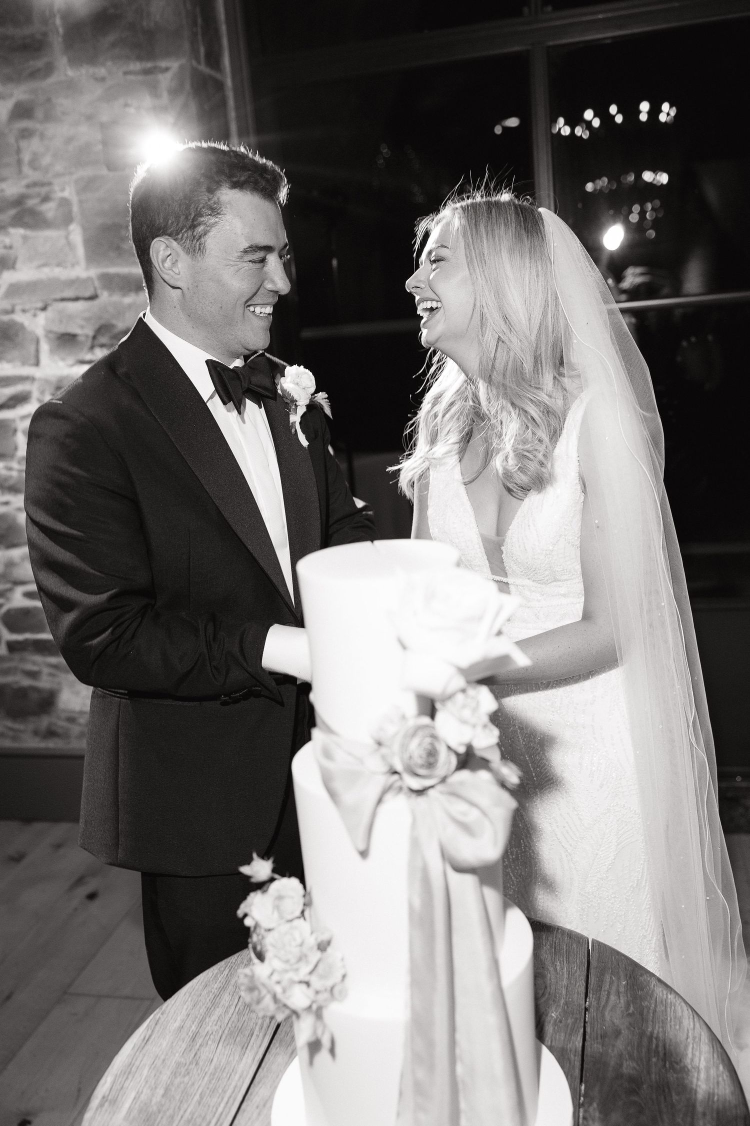 A couple shares a joyful moment during their wedding celebration in black and white photography.