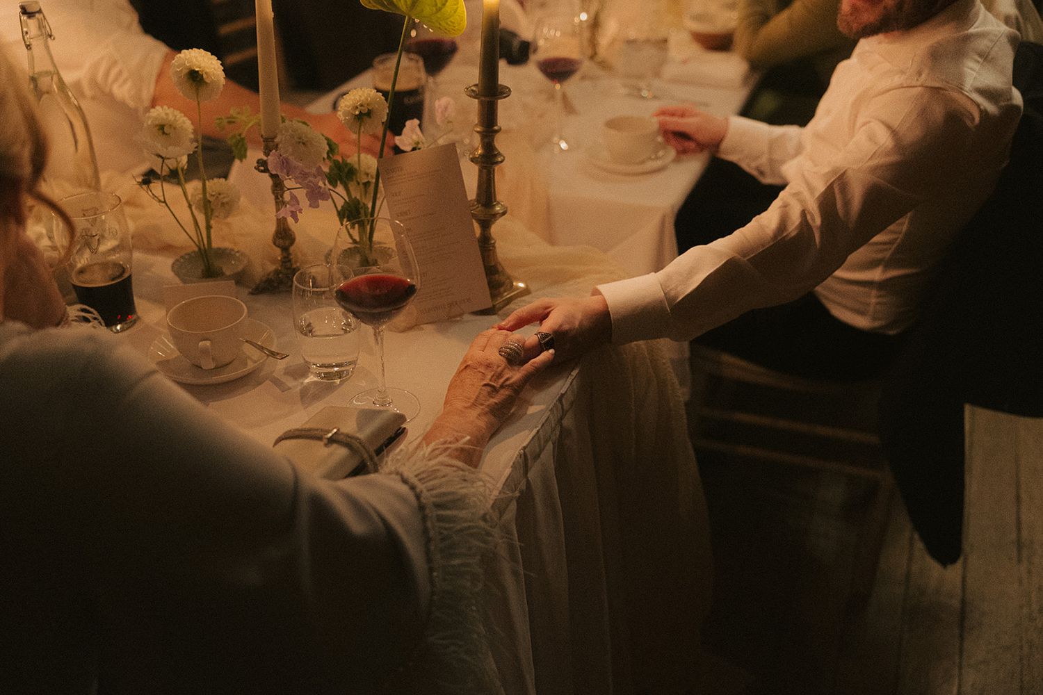 Hands pouring red wine into glasses during an elegant dinner party service at a restaurant.