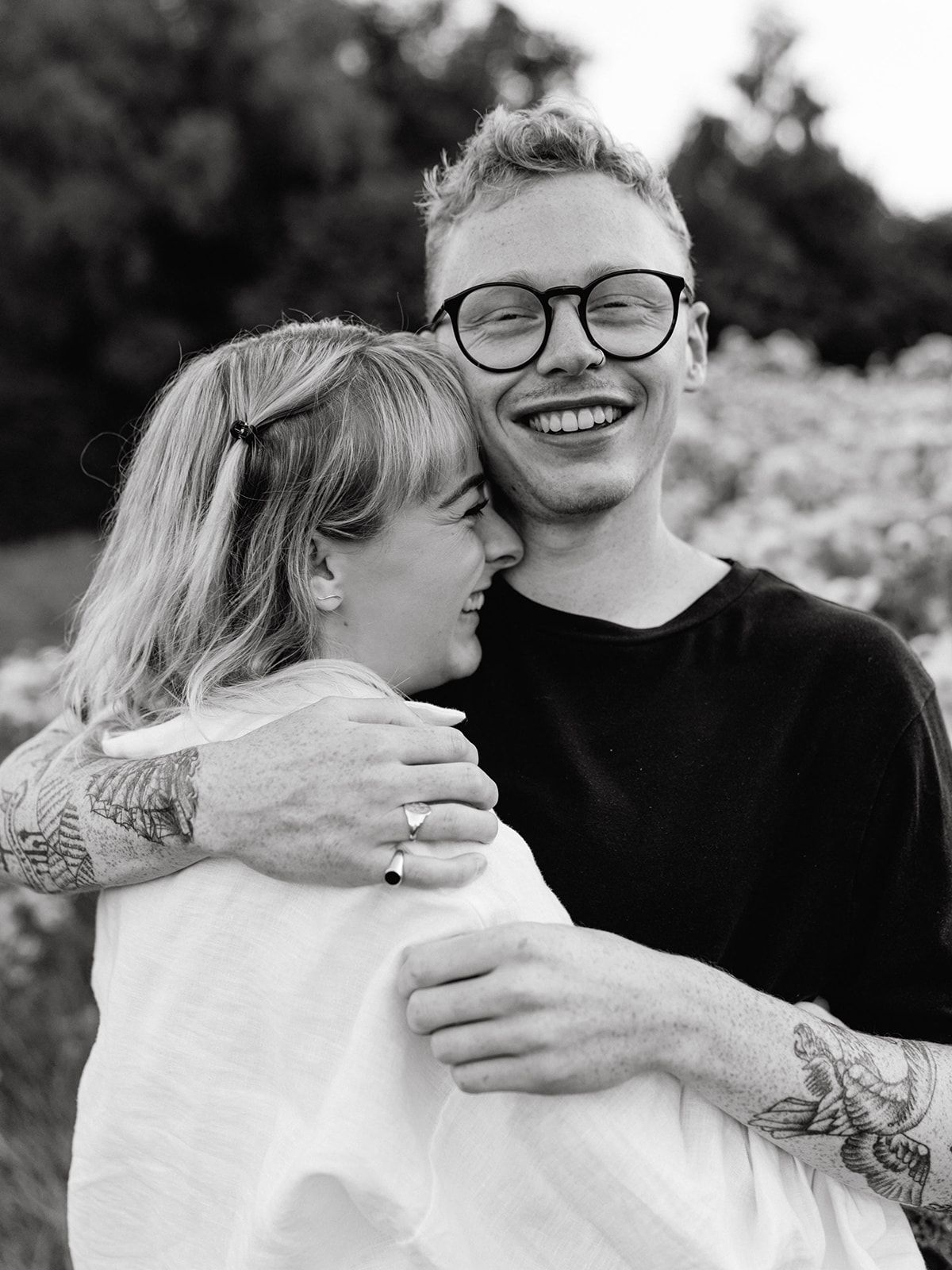 Intimate black and white portraits of a couple sharing joyful embraces outdoors.