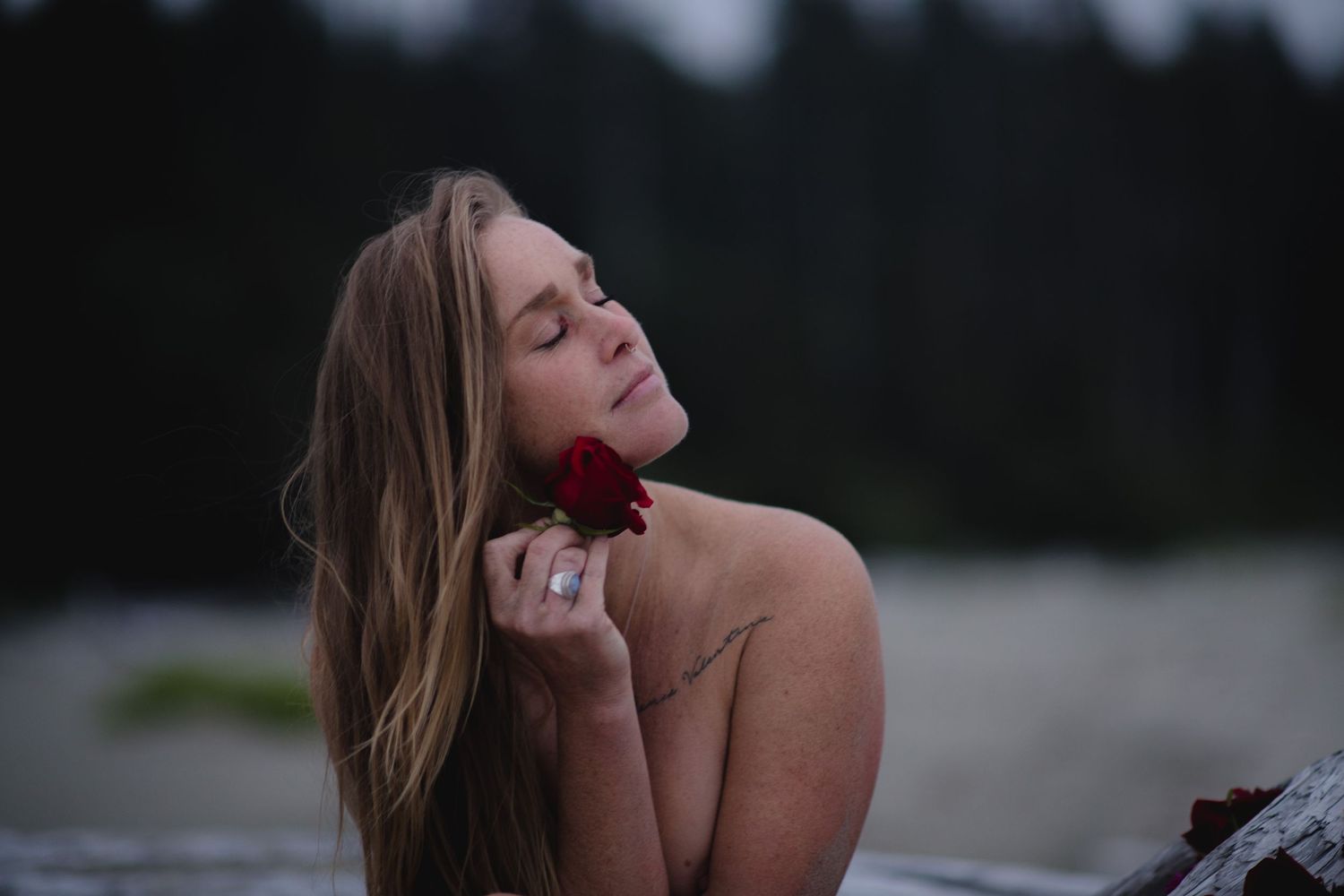 Artistic outdoor portrait showing long hair flowing in the breeze against a forested background.