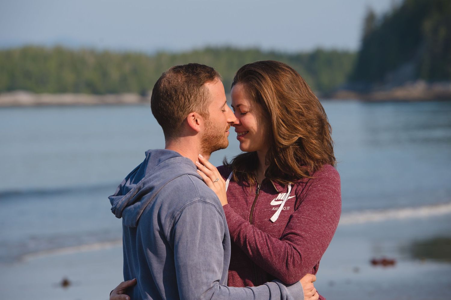 A couple embraces by a scenic lakeside at sunset, creating a romantic silhouette against the water.