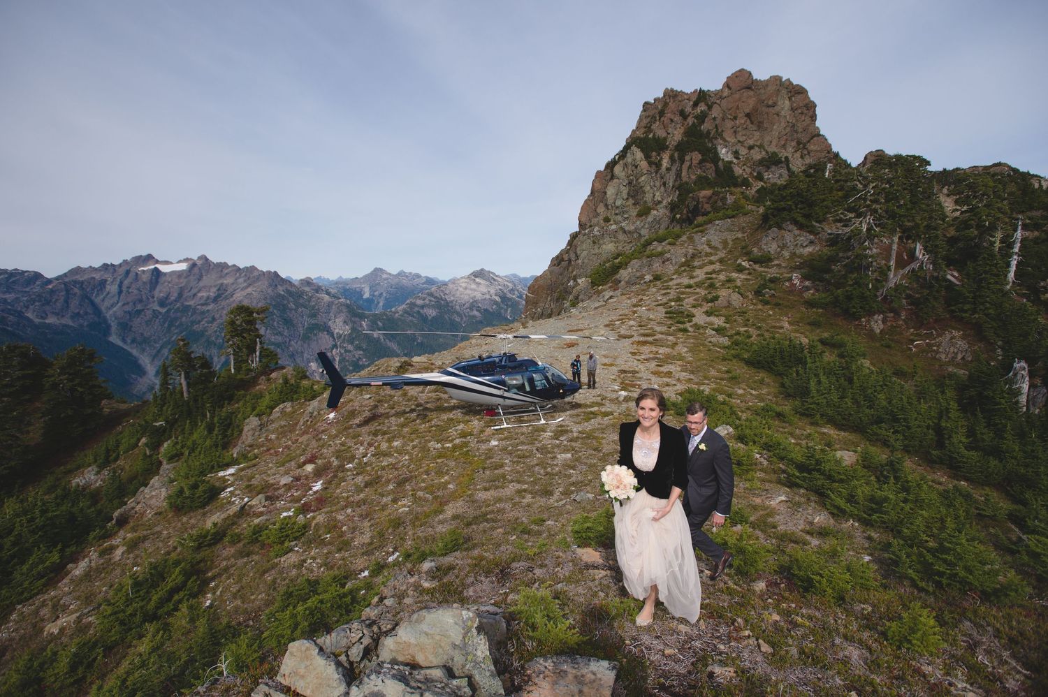 Wedding ceremony participants gather on a rocky mountain peak with panoramic views.