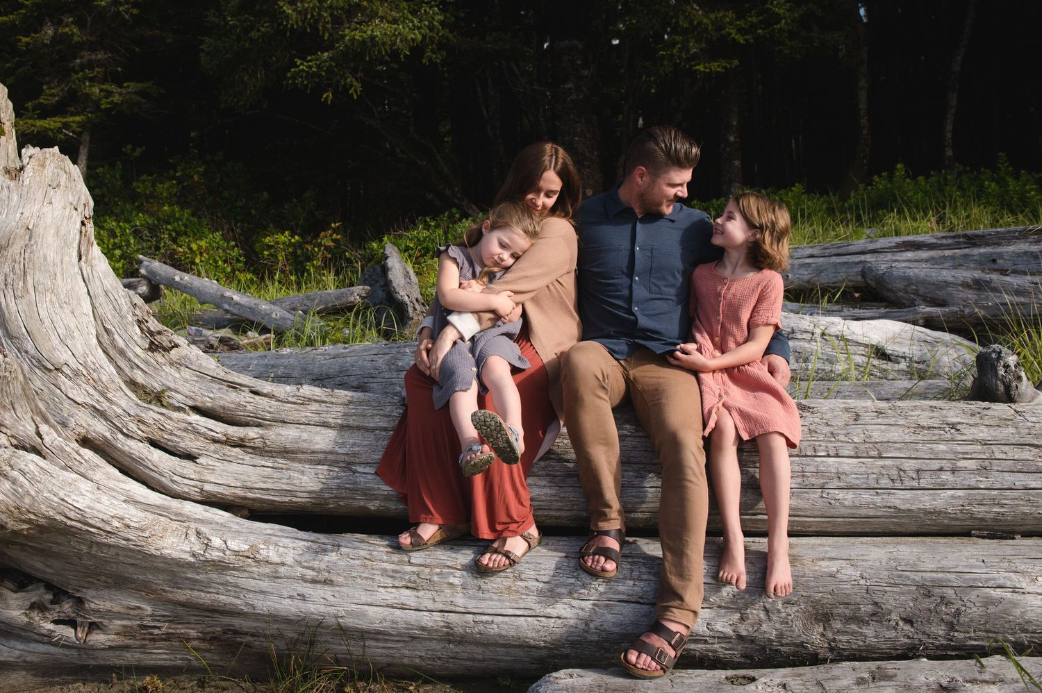 Group sitting together on a large driftwood log at the beach.