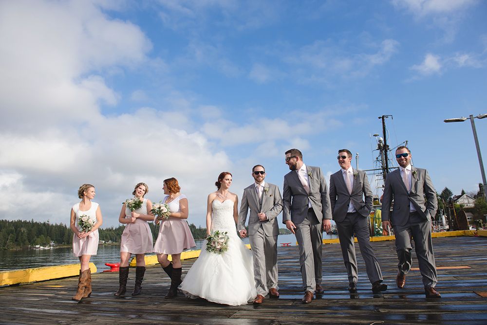 Wedding party lined up for photos against blue sky and waterfront.