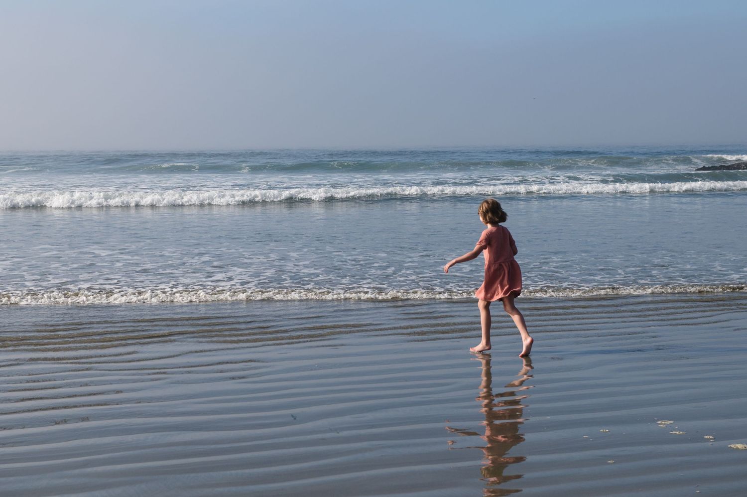 Children playing in the shallow waves at the ocean's edge.