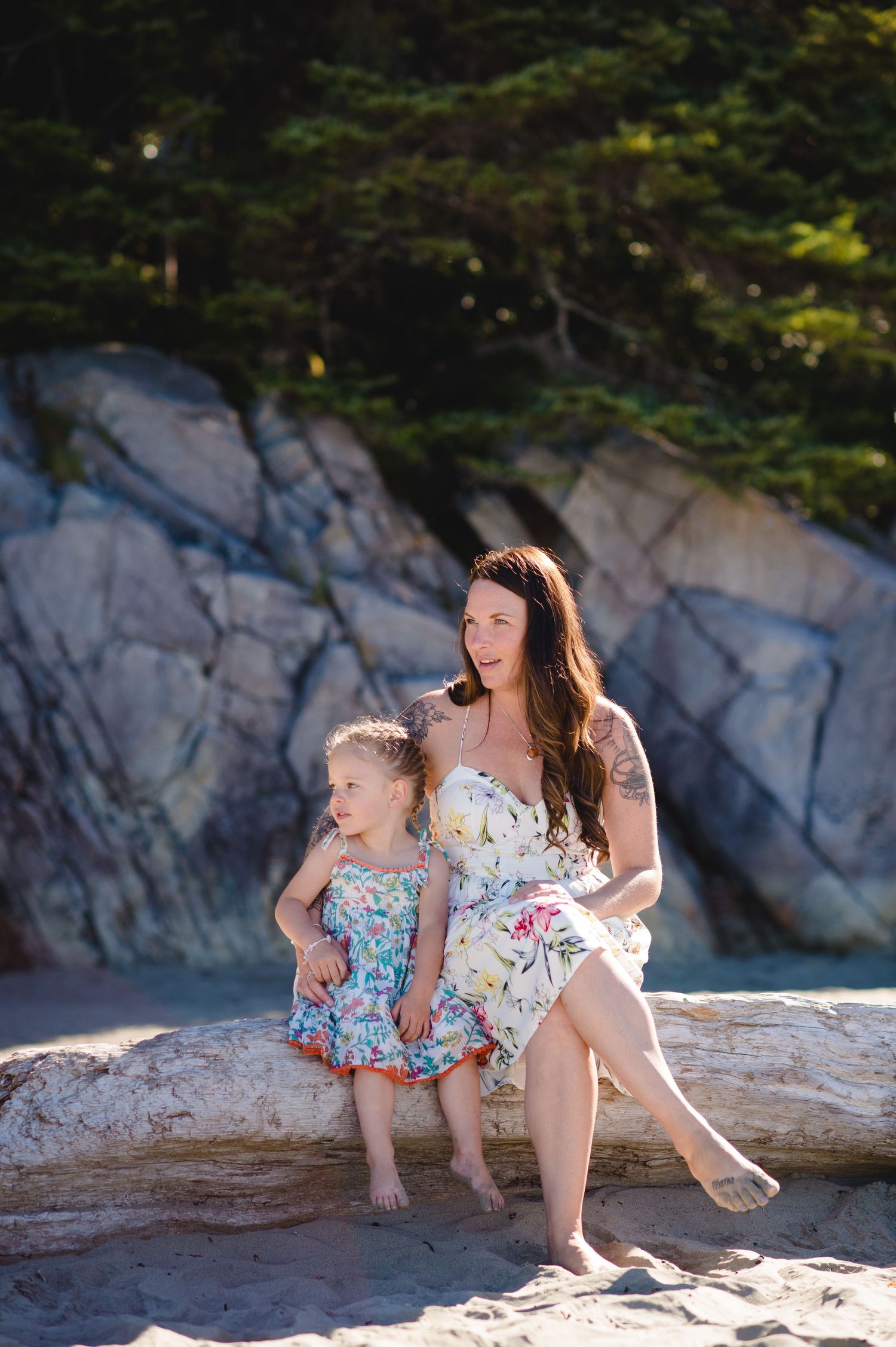 Family enjoying a peaceful moment together on a rocky beach with dramatic cliff backdrop.