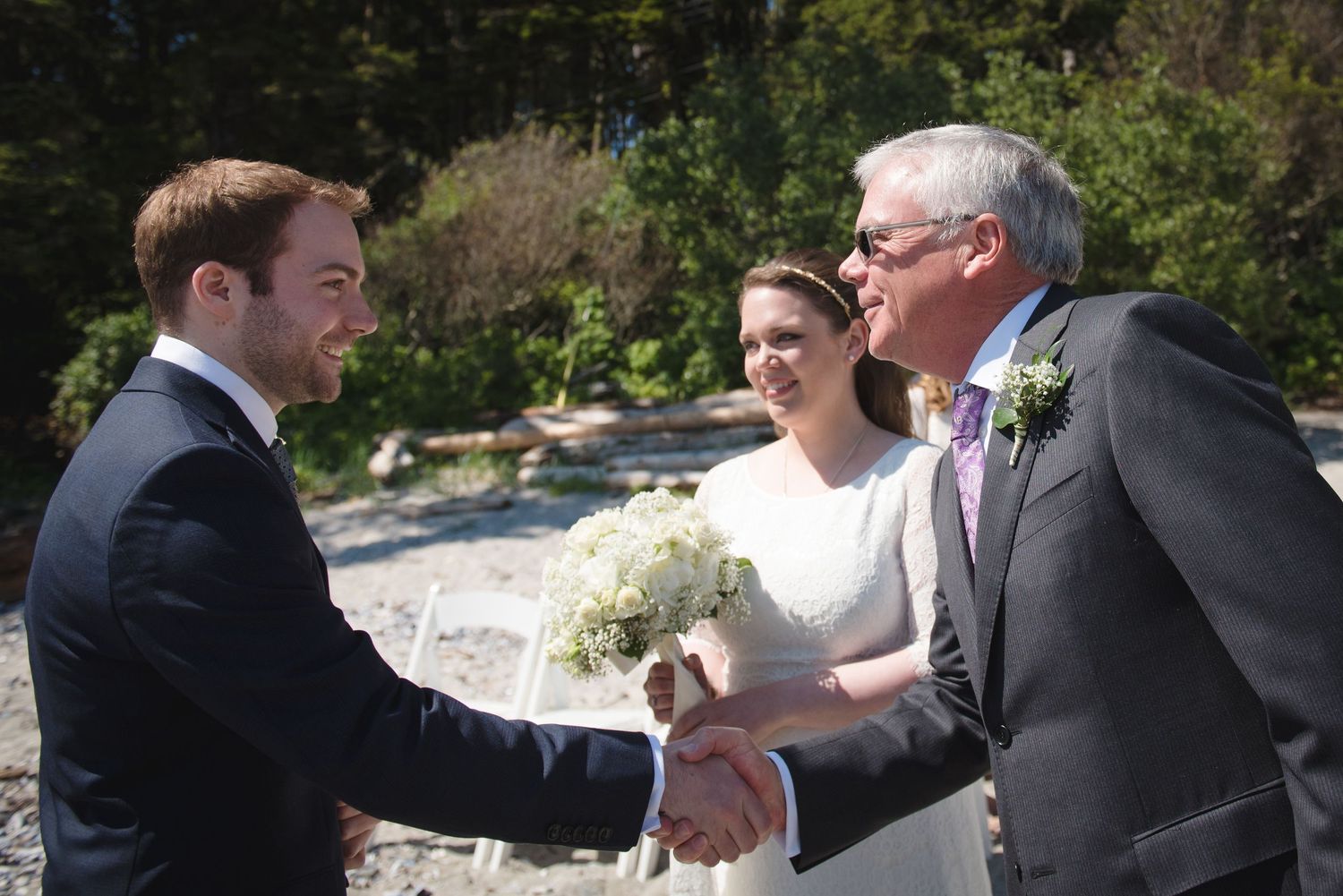 Wedding party members greeting and congratulating each other outdoors.
