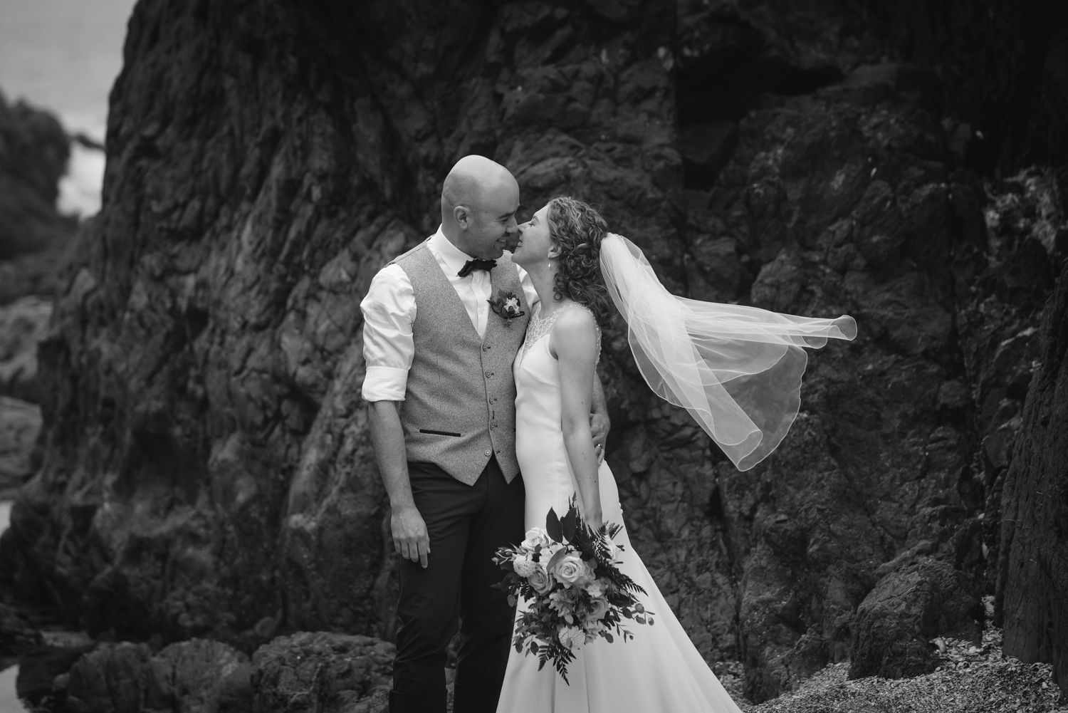 Black and white wedding photos showing romantic moments between newlyweds against a dramatic rocky backdrop.