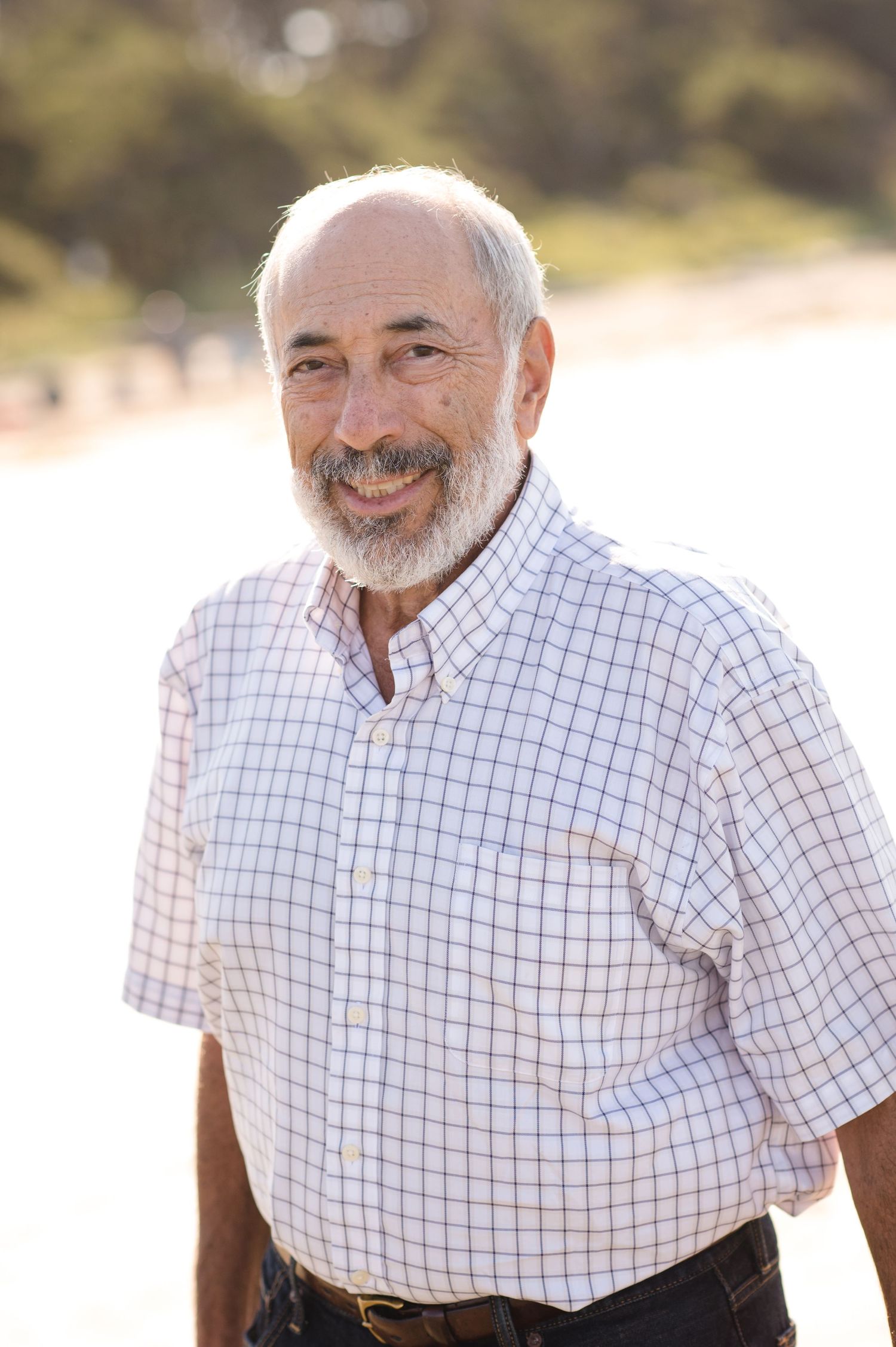 Close-up portrait series of a man in checkered shirt smiling at the beach.
