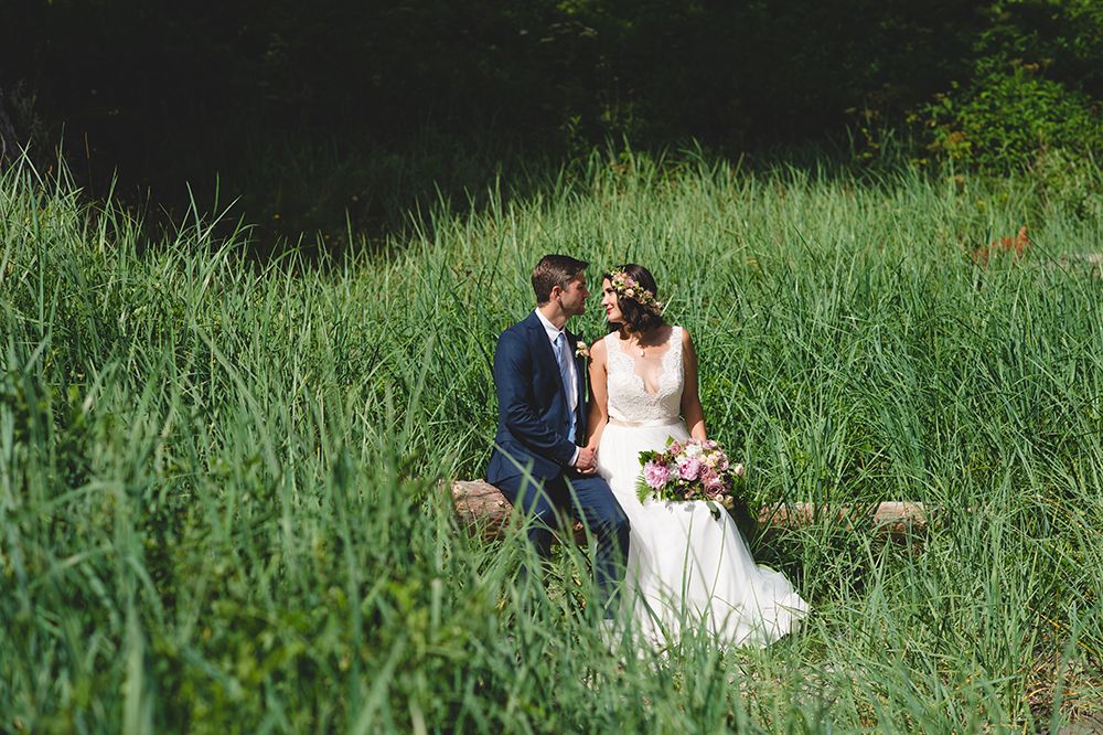 Wedding couple photographed in tall grass with natural outdoor scenery.