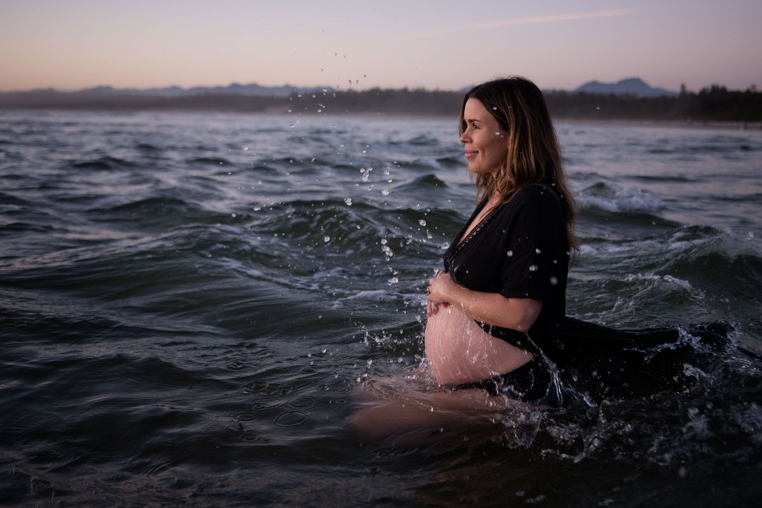 Figure immersed in dark water during twilight with splashing waves.