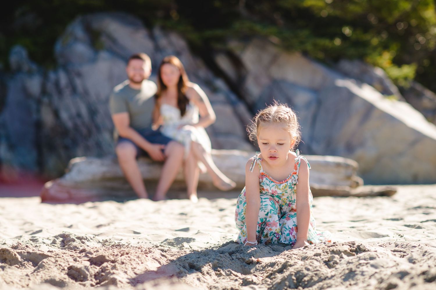 Beautiful beach scene with family members relaxing on sandy shore near rocky cliffs.